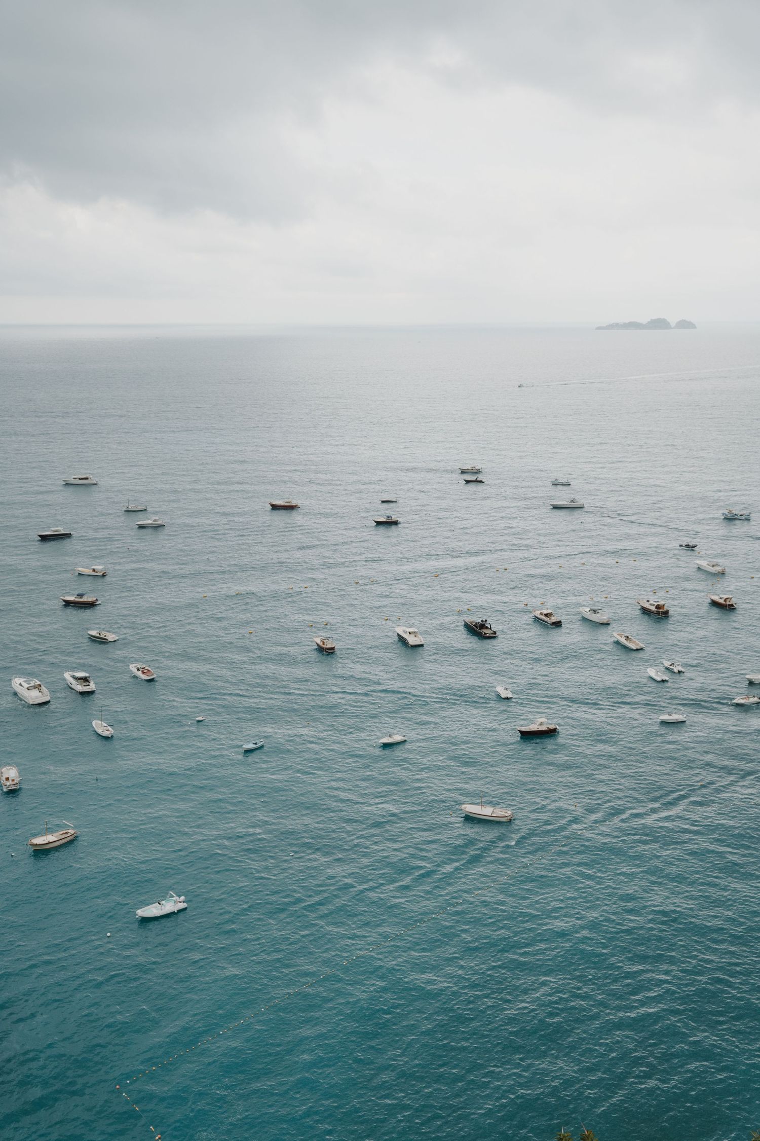 Aerial view of boats and yachts scattered across turquoise Mediterranean waters.