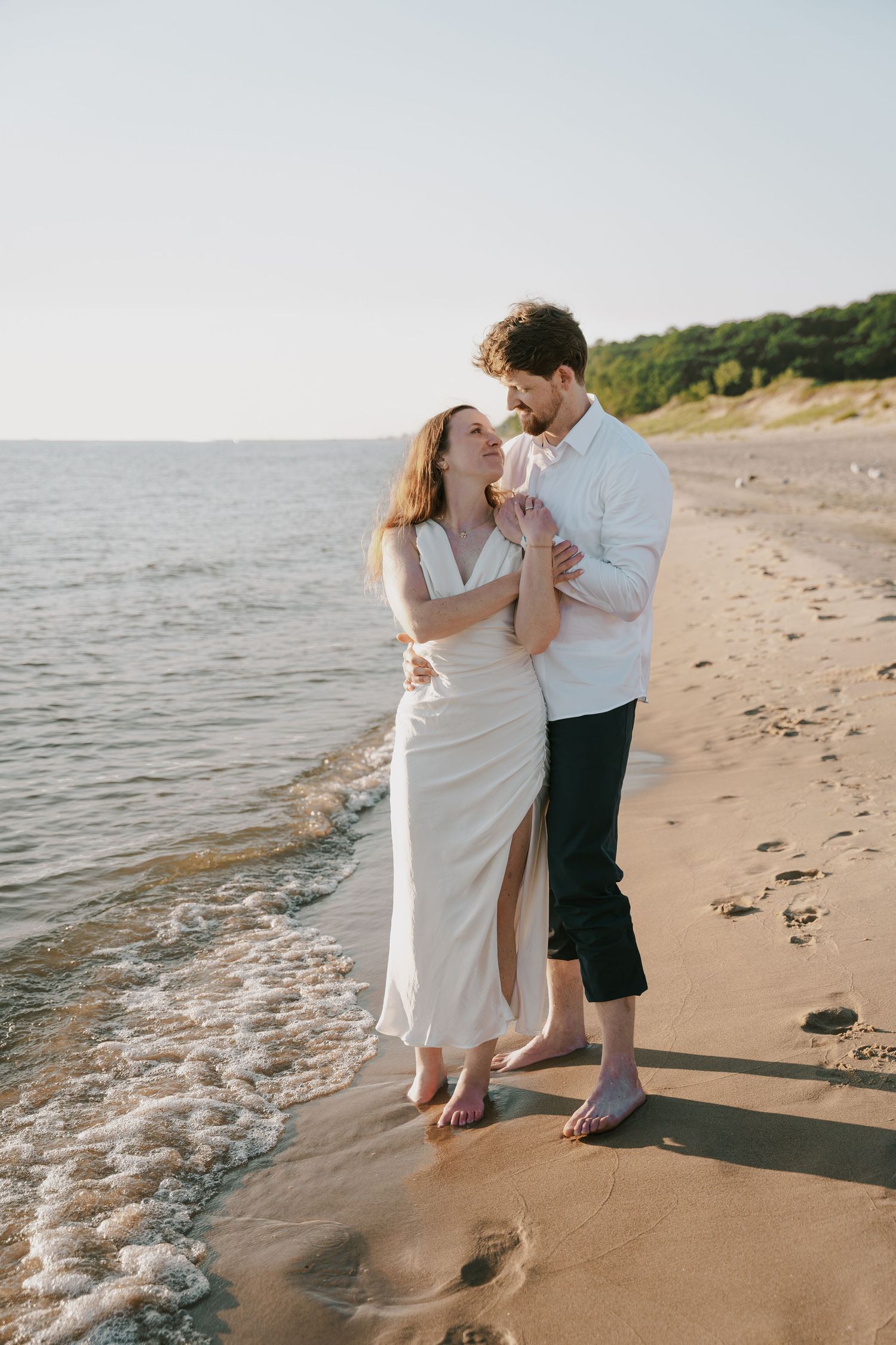 A couple shares an intimate dance along the water's edge at sunset.