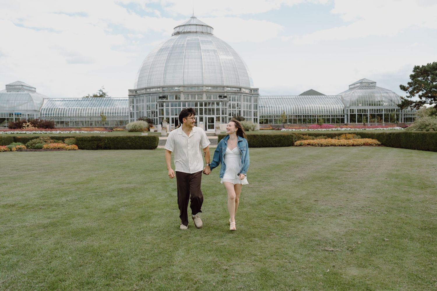 Playful scene on the lawn in front of a glass-domed botanical garden structure.