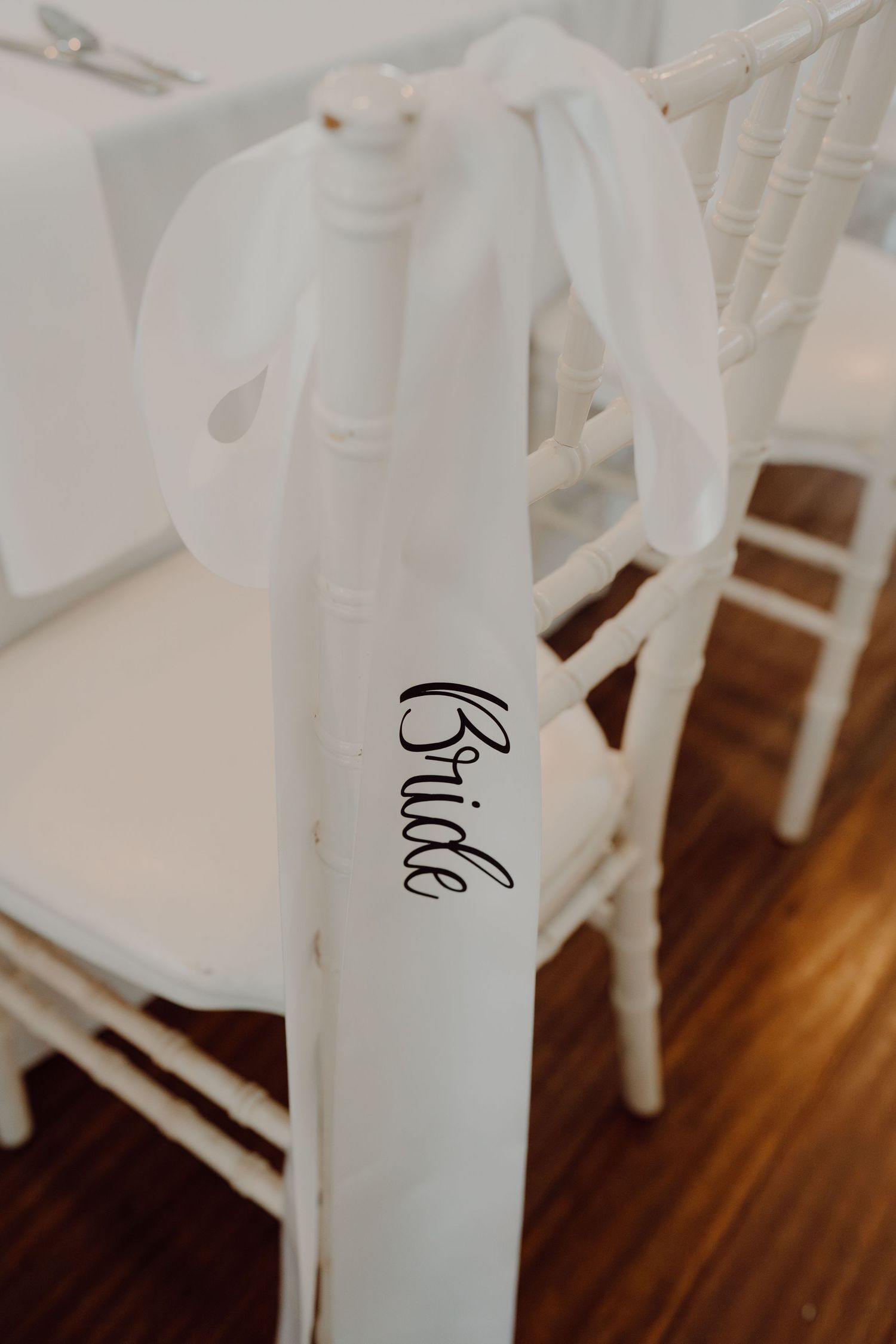 White chair covers with calligraphy text tied with ribbons at formal event.