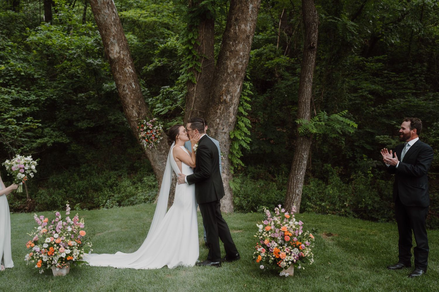 Outdoor wedding ceremony with lush greenery and colorful floral arrangements.