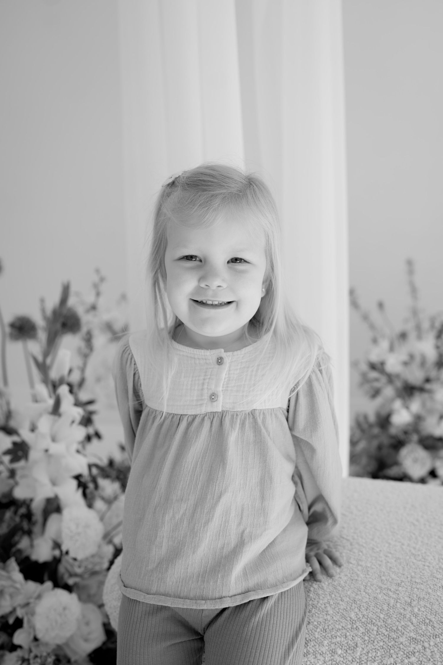 Joyful portrait in a minimalist setting with floral accents.
