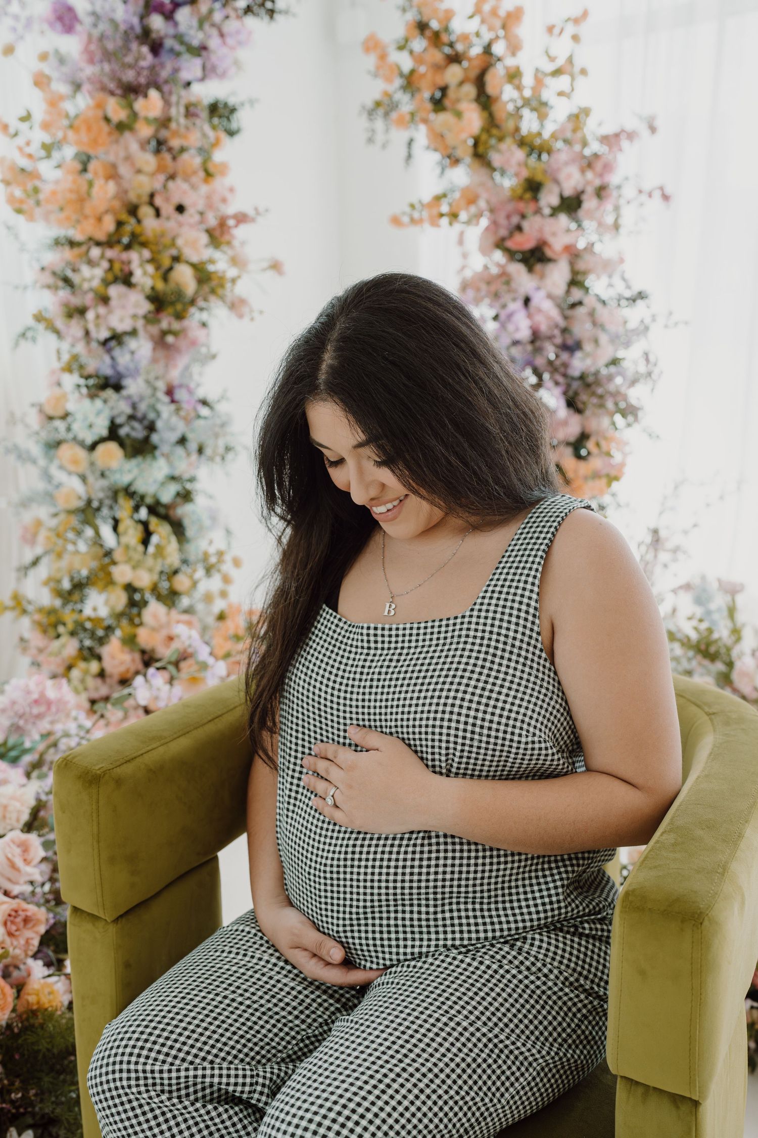 Intimate maternity moment captured with woman in gingham outfit touching baby bump.
