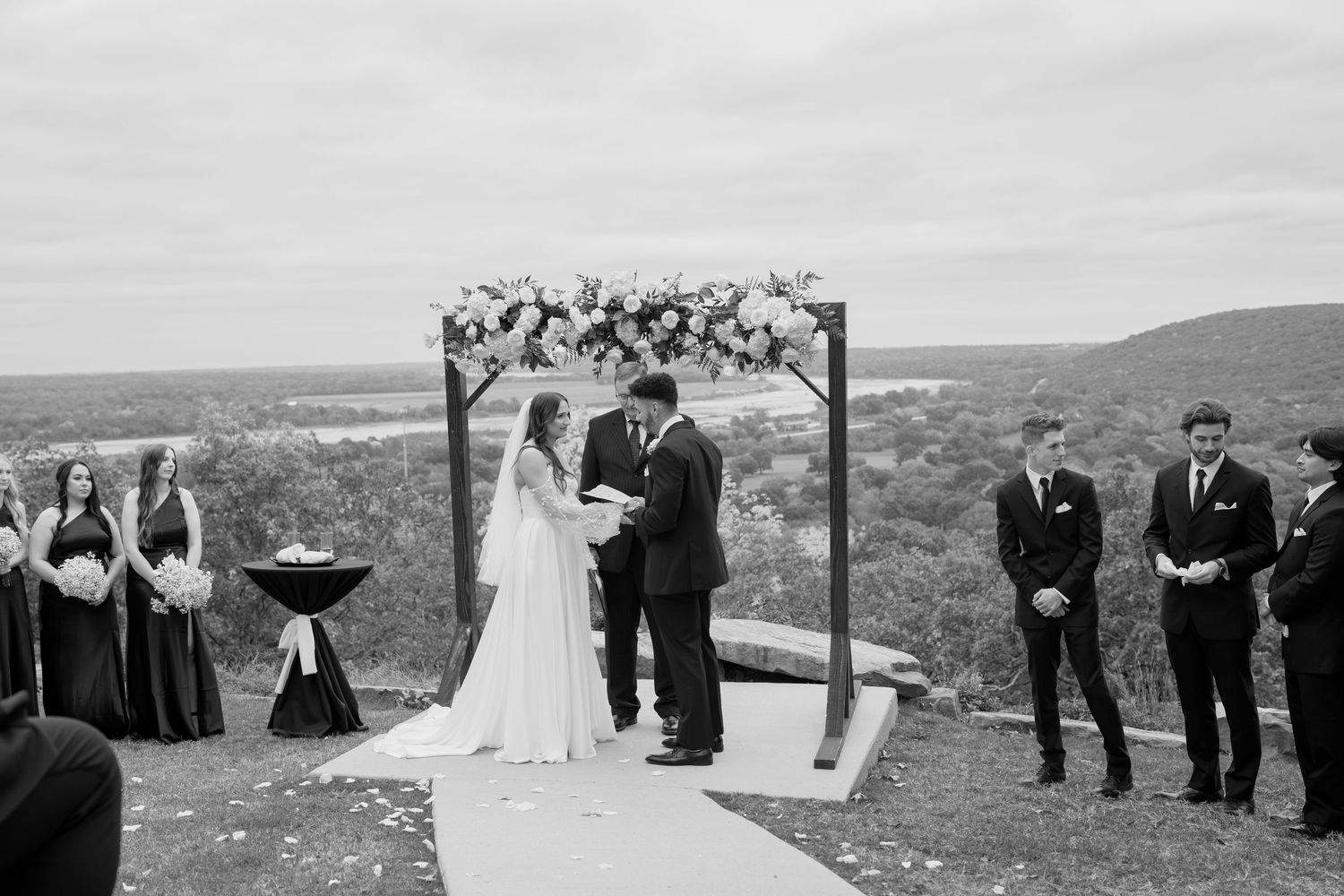 Wedding party arranged on hilltop with scenic valley views during outdoor ceremony.
