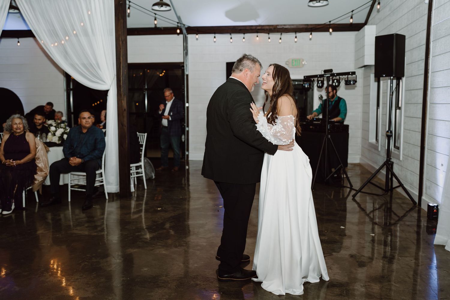 Wedding reception dance floor with white draping and string lights creating a romantic atmosphere.