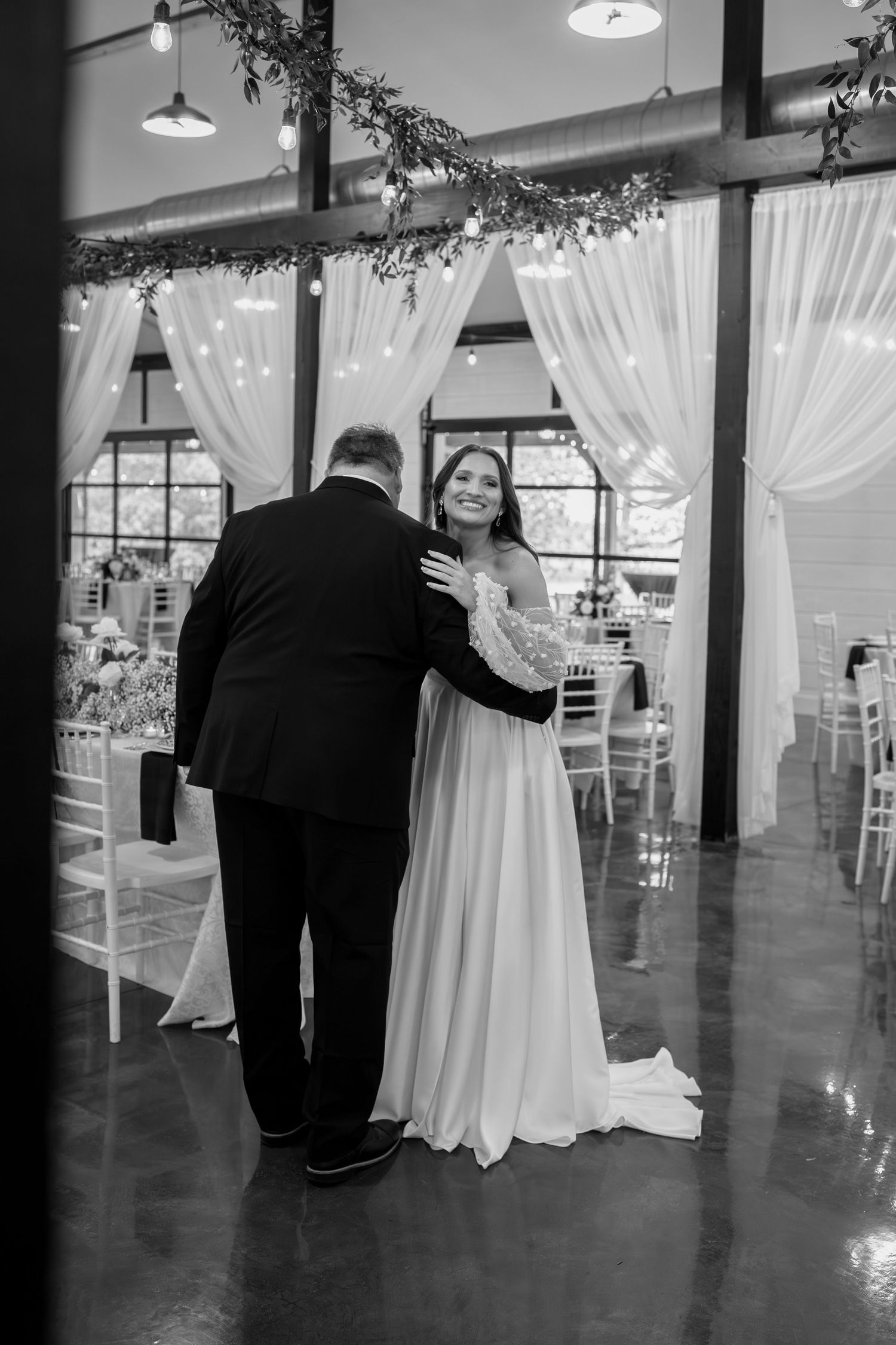 A black and white photo captures an emotional first look moment in an elegant wedding venue.