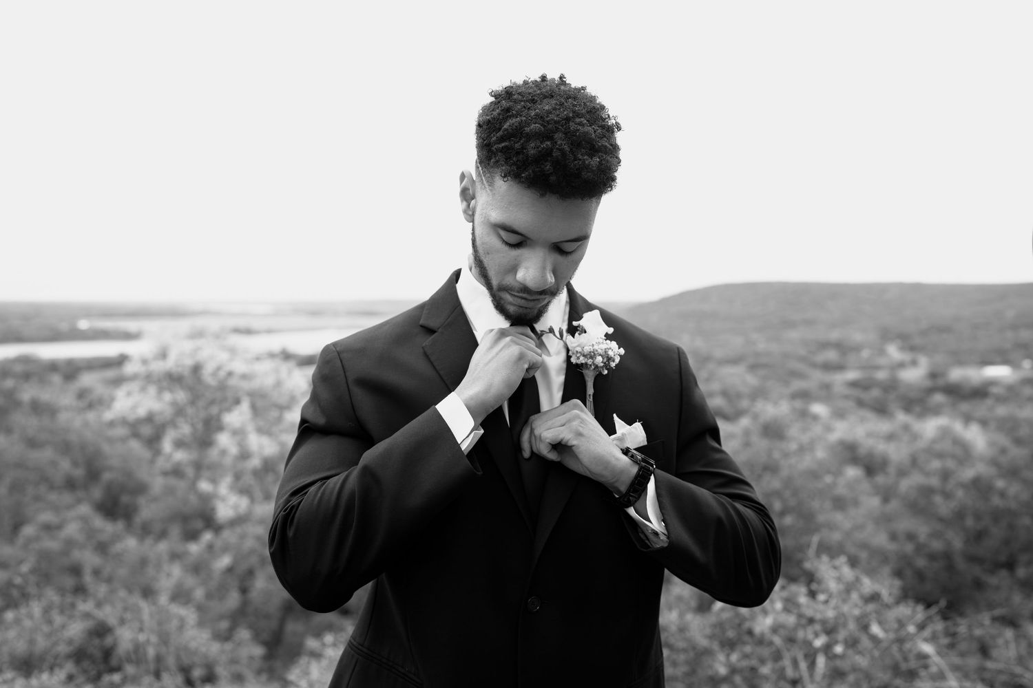 Person in formal attire wipes tears during emotional outdoor wedding moment.