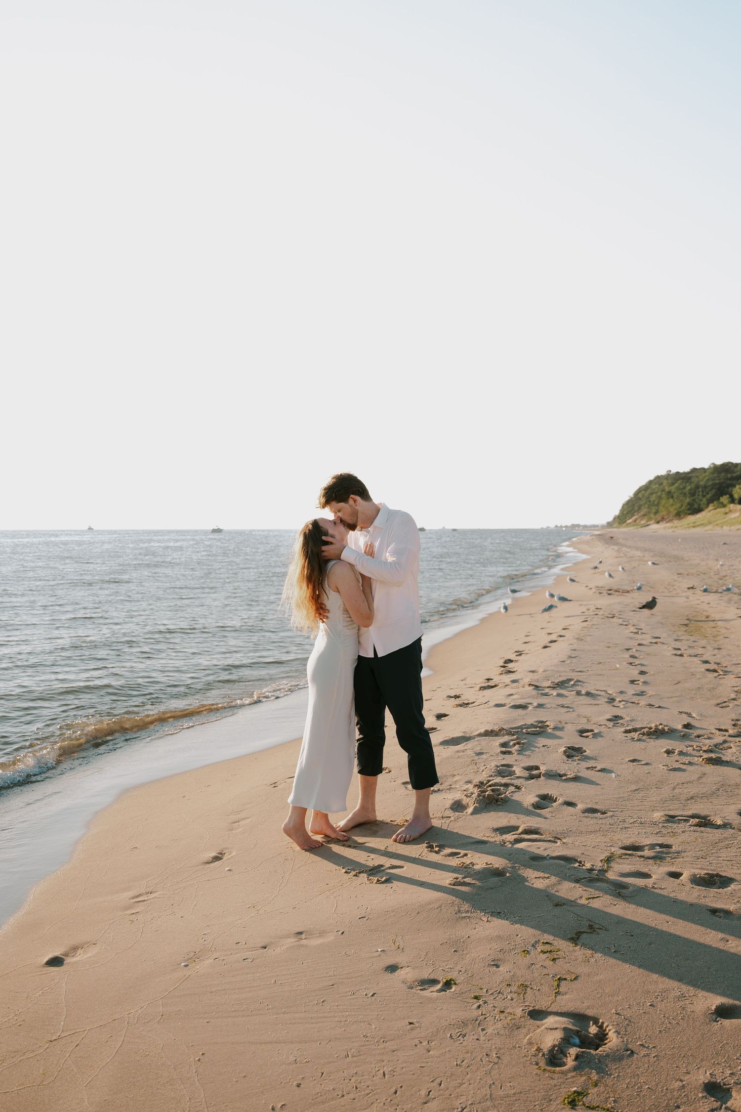 Intimate beach photoshoot featuring a couple in white and black attire along the shoreline.