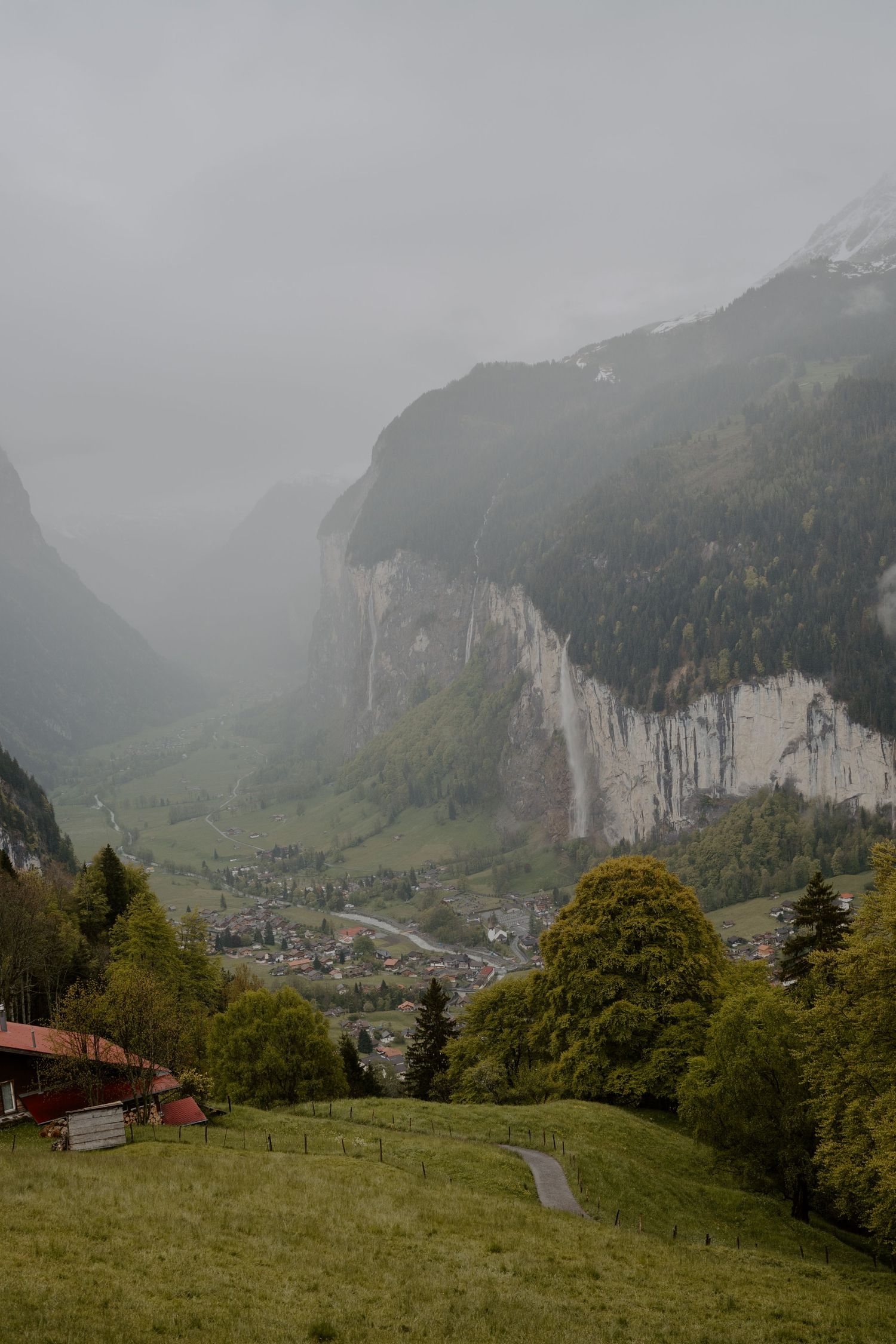 Majestic Lauterbrunnen Valley with waterfalls and Swiss Alps in foggy conditions.