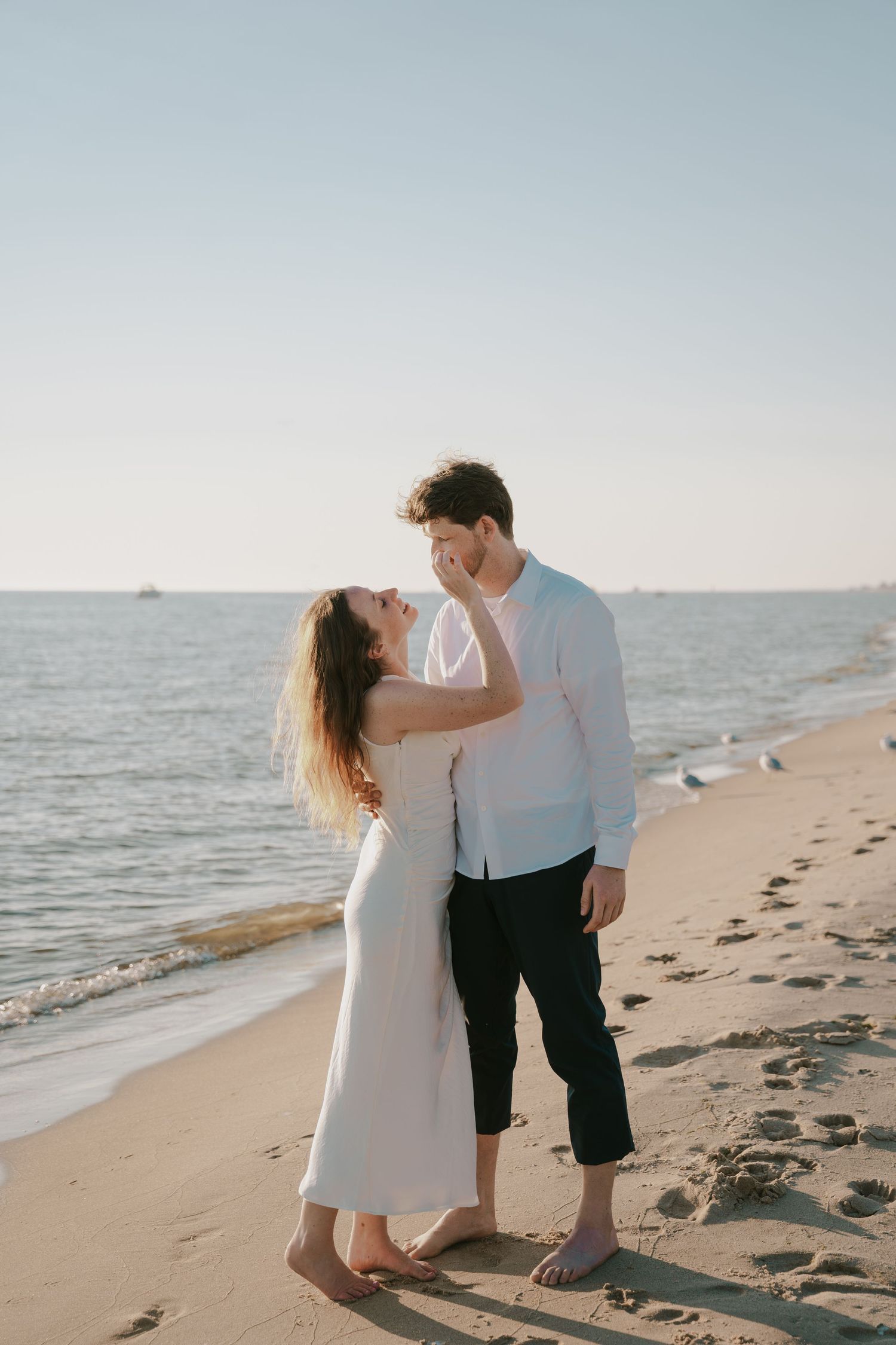 Romantic seaside moment captured between couple in casual beach attire.