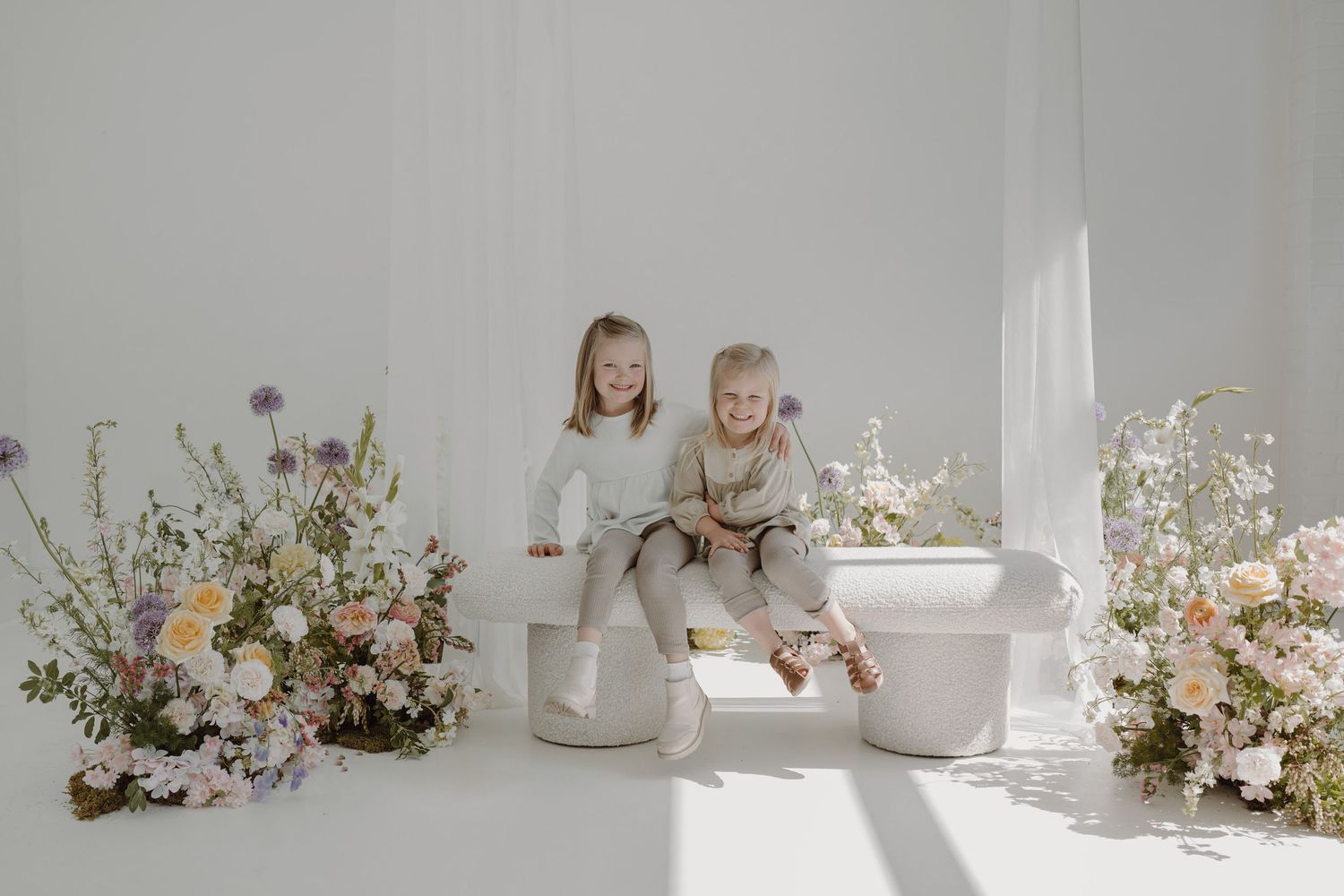Modern white studio setting with artistic ceramic vessels and blooming flower arrangements.