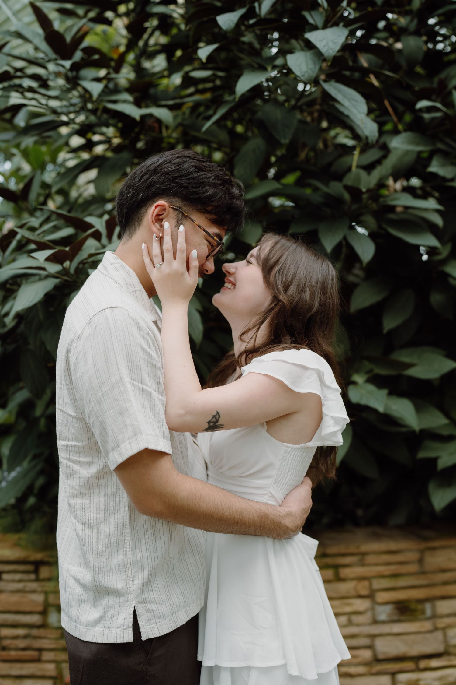 A couple in white clothing embracing and sharing intimate moments in a garden setting.