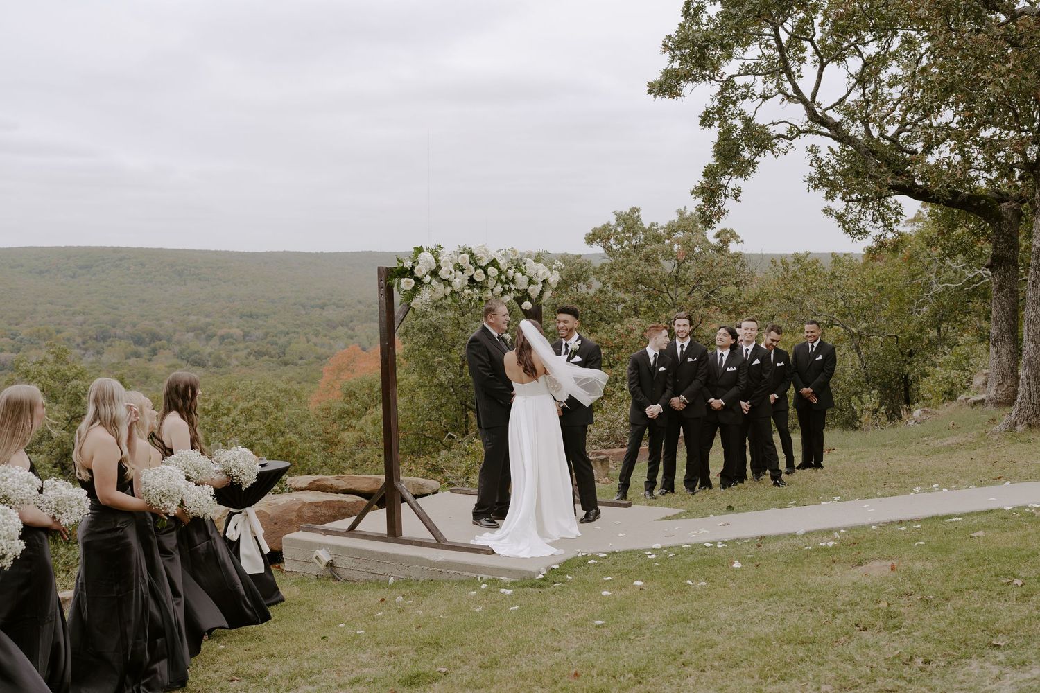 Wedding ceremony taking place on a scenic overlook with rolling hills in the background.