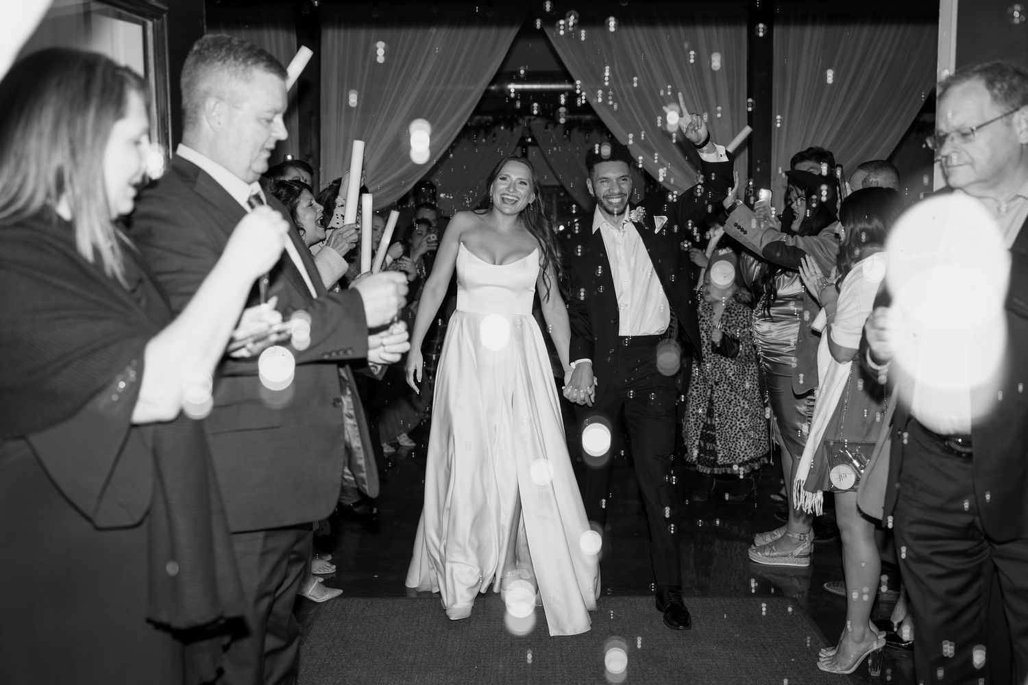 Wedding party dancing and celebrating during an evening reception with dramatic lighting.