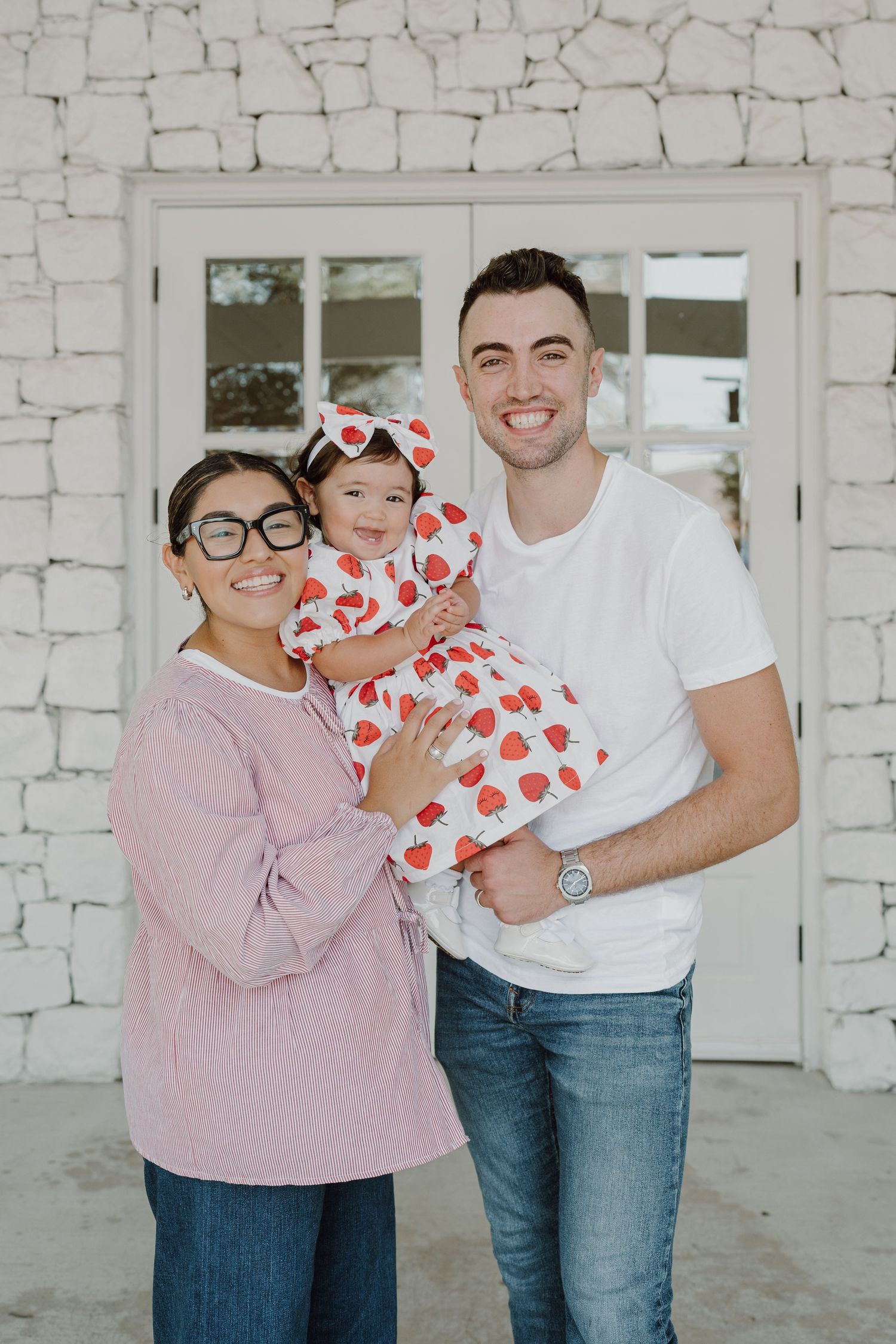 Candid family photo showing joyful interaction against white stone backdrop.