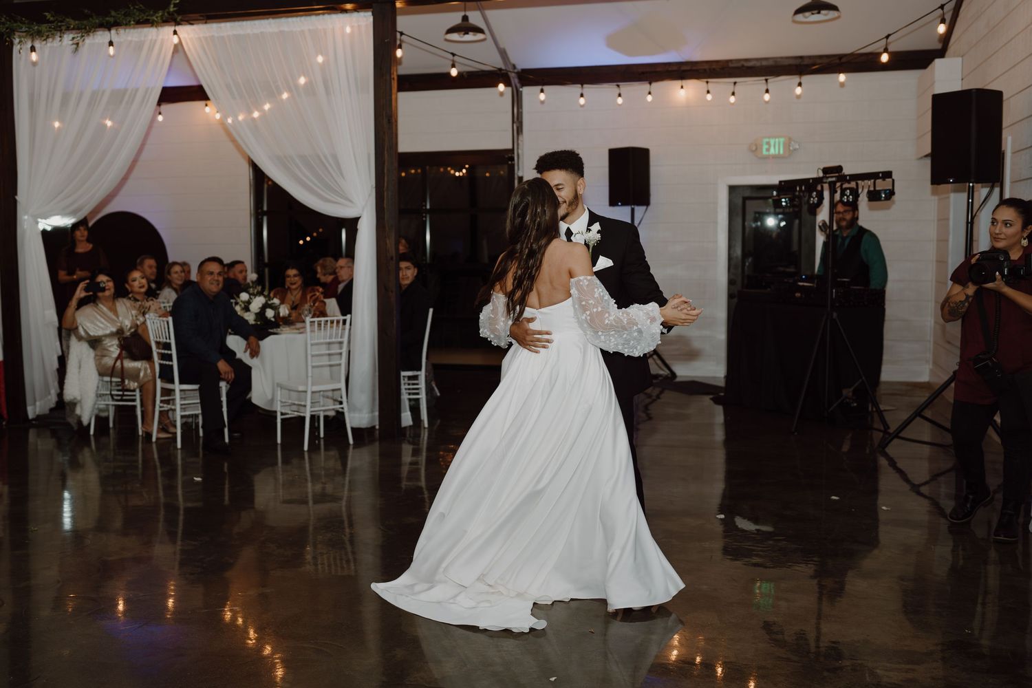 Wedding reception dance floor scene with white draping and twinkling lights overhead.