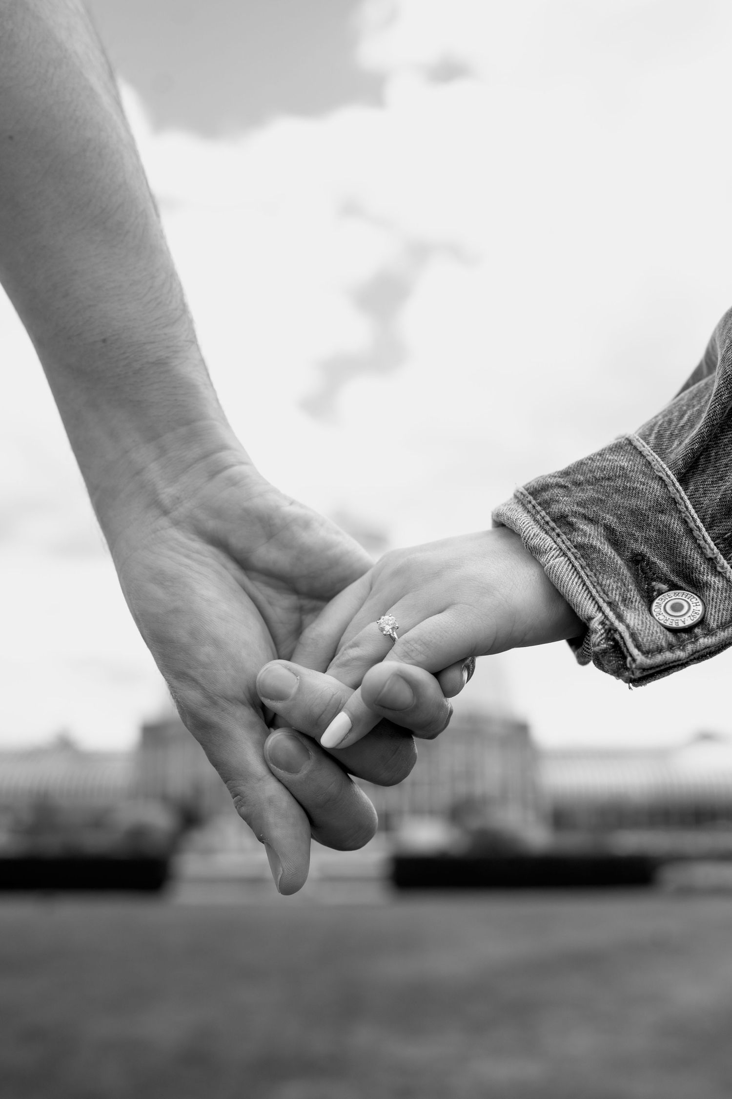 Black and white close-up of hands holding each other against a blurred background.