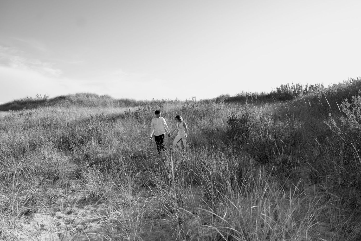 A black and white image of two people walking through a misty coastal landscape.
