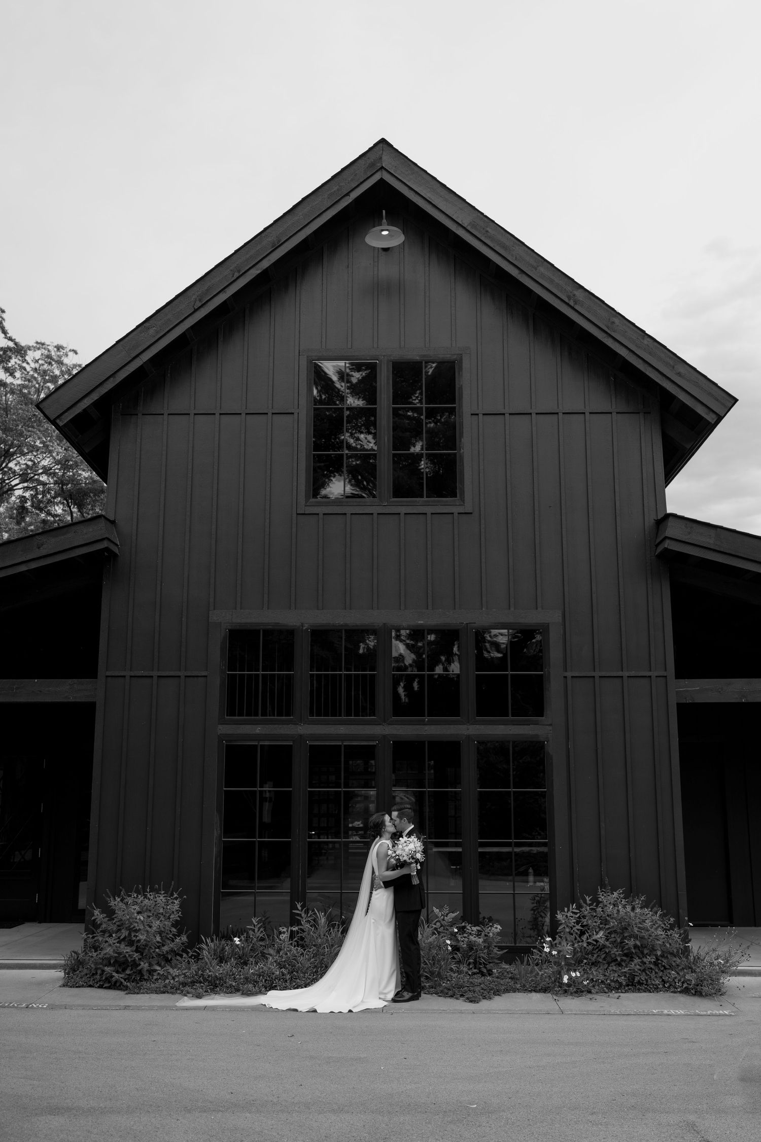 Spain Ranch's black barn wedding venue with floor-to-ceiling windows and landscaped garden entrance.