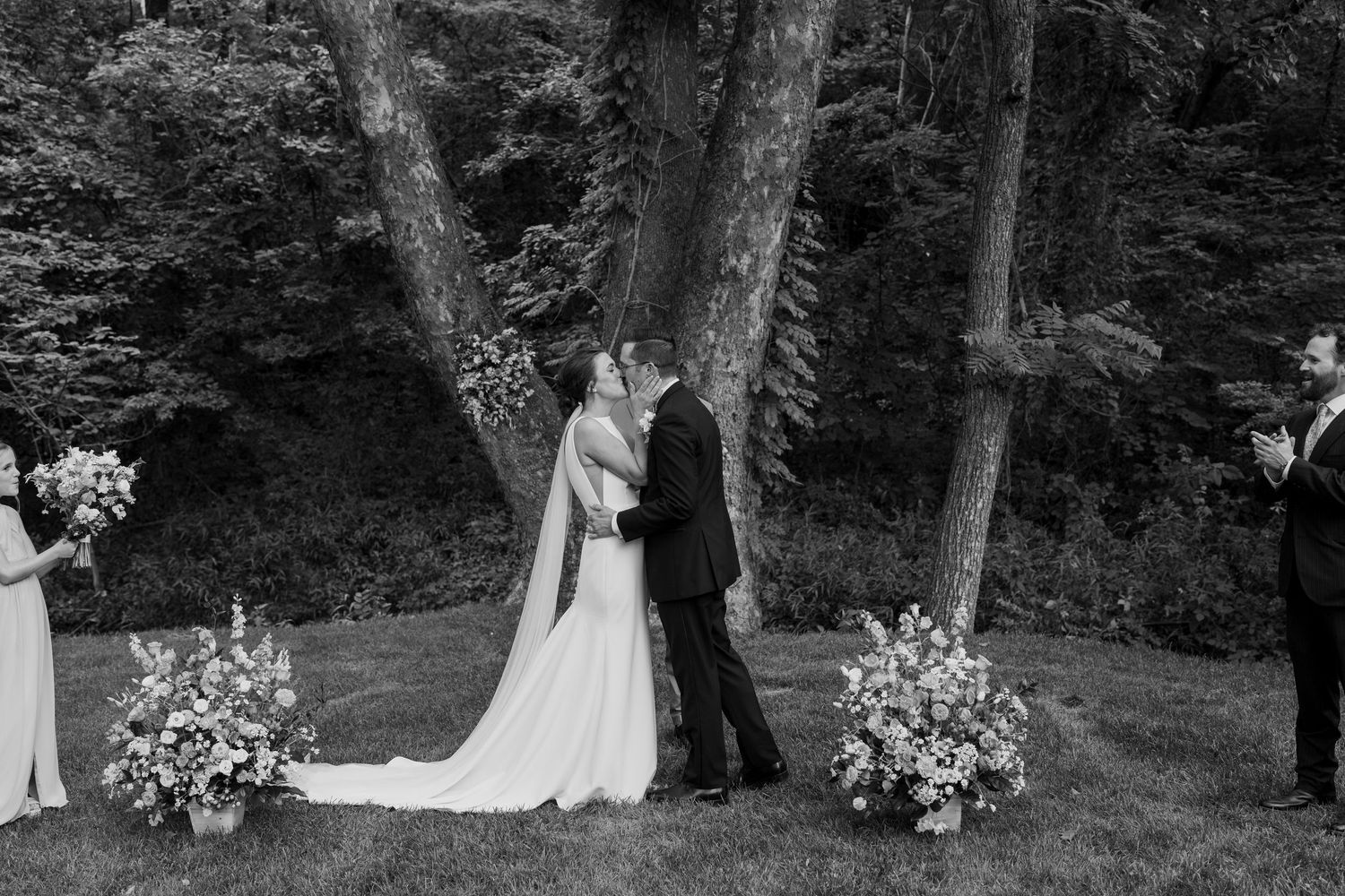 Black and white wedding ceremony moments captured in a serene forest backdrop.