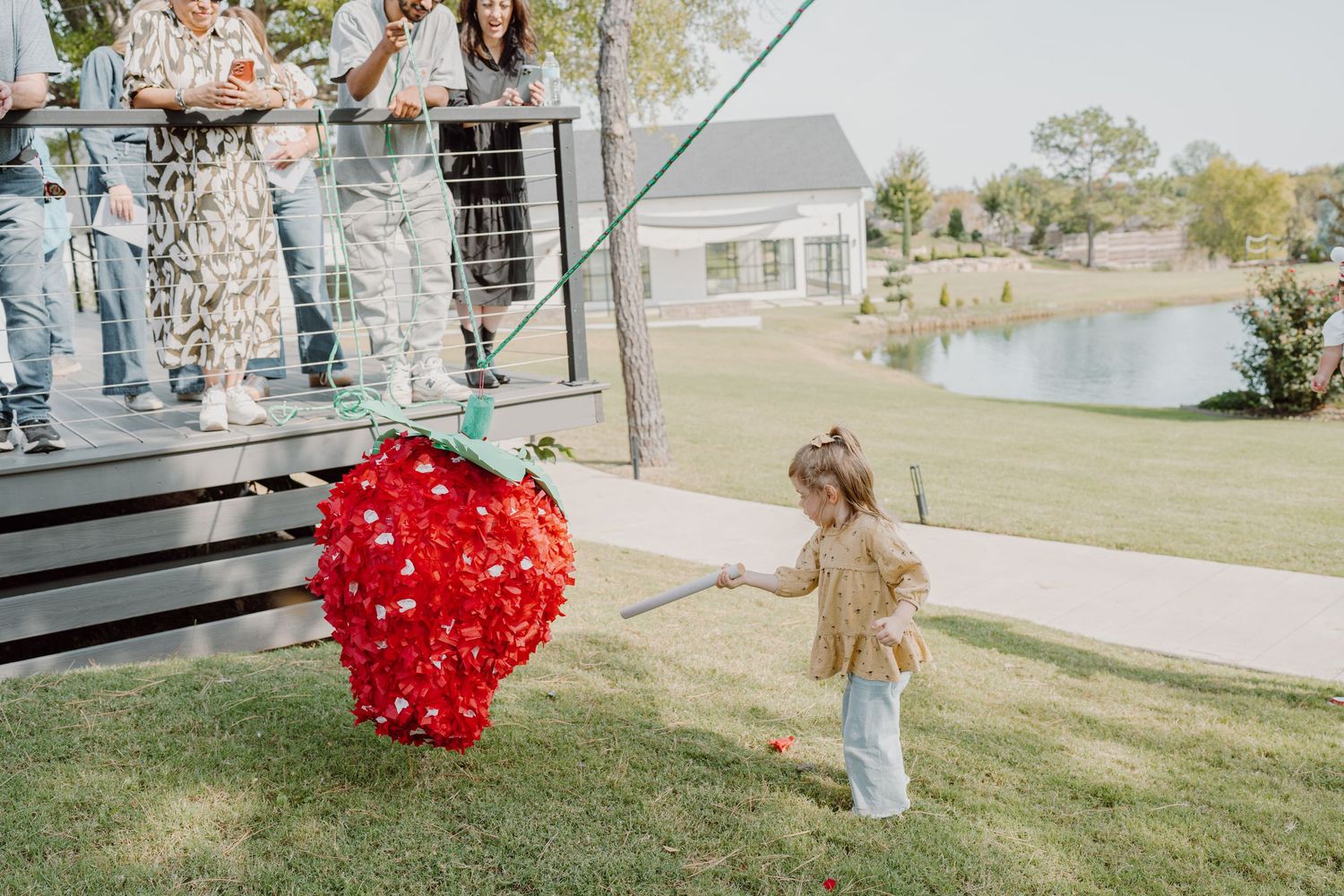 A group gathers outdoors near a large red heart-shaped balloon display on a grassy lawn.