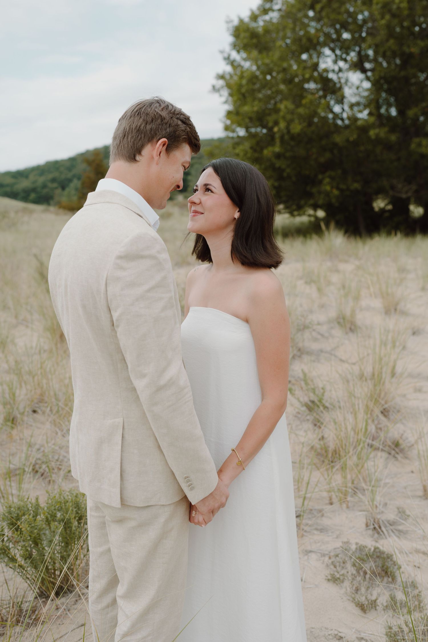 A romantic wedding portrait captured in natural dune landscape with soft lighting.