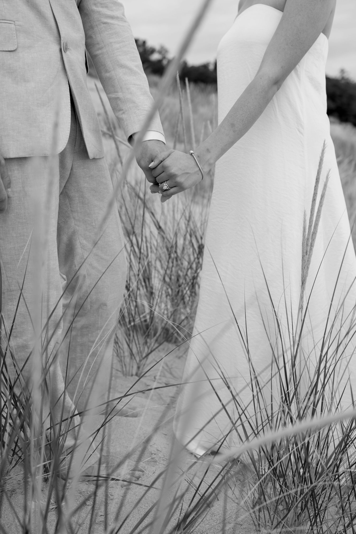 Black and white photograph of formal attire details among coastal dune grass.