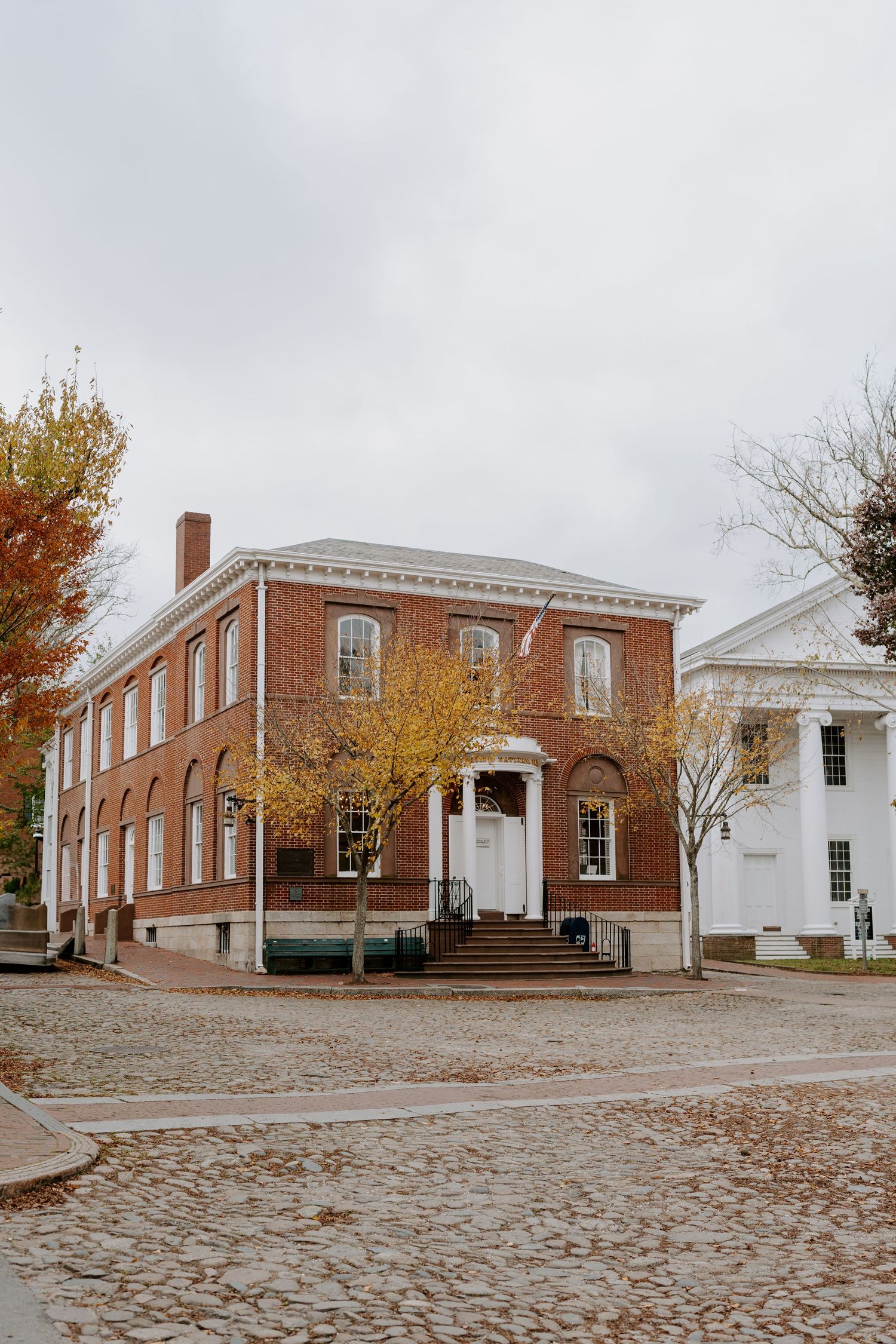 Panoramic view of historic brick buildings with white columns and cobblestone courtyard.