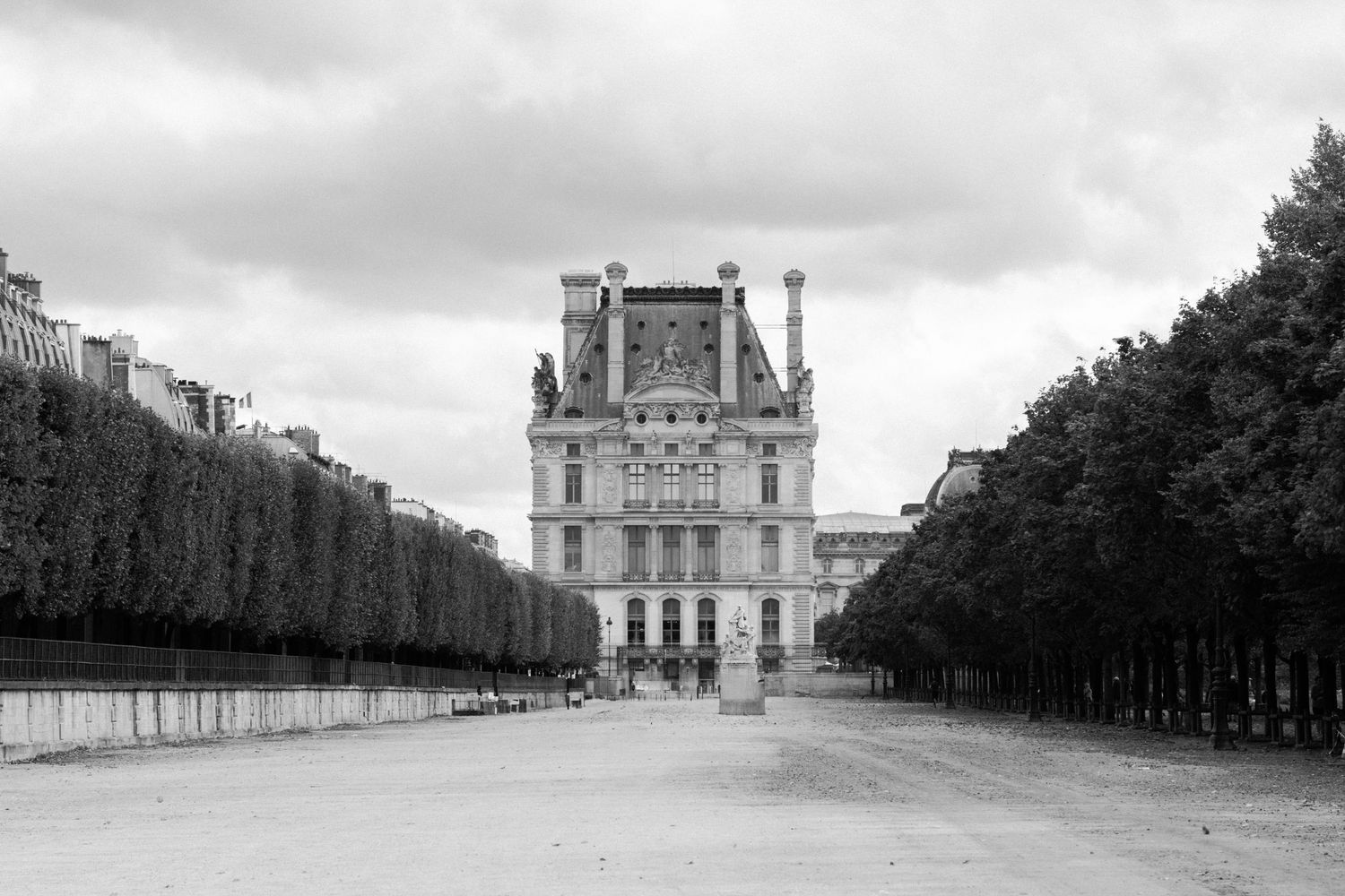 Black and white panorama of grand palace building with tree-lined path and formal gardens.