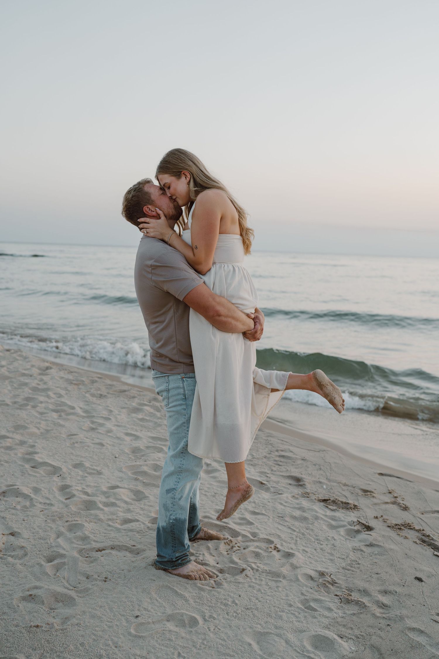 A romantic beach photoshoot captures tender moments between a couple at sunset.