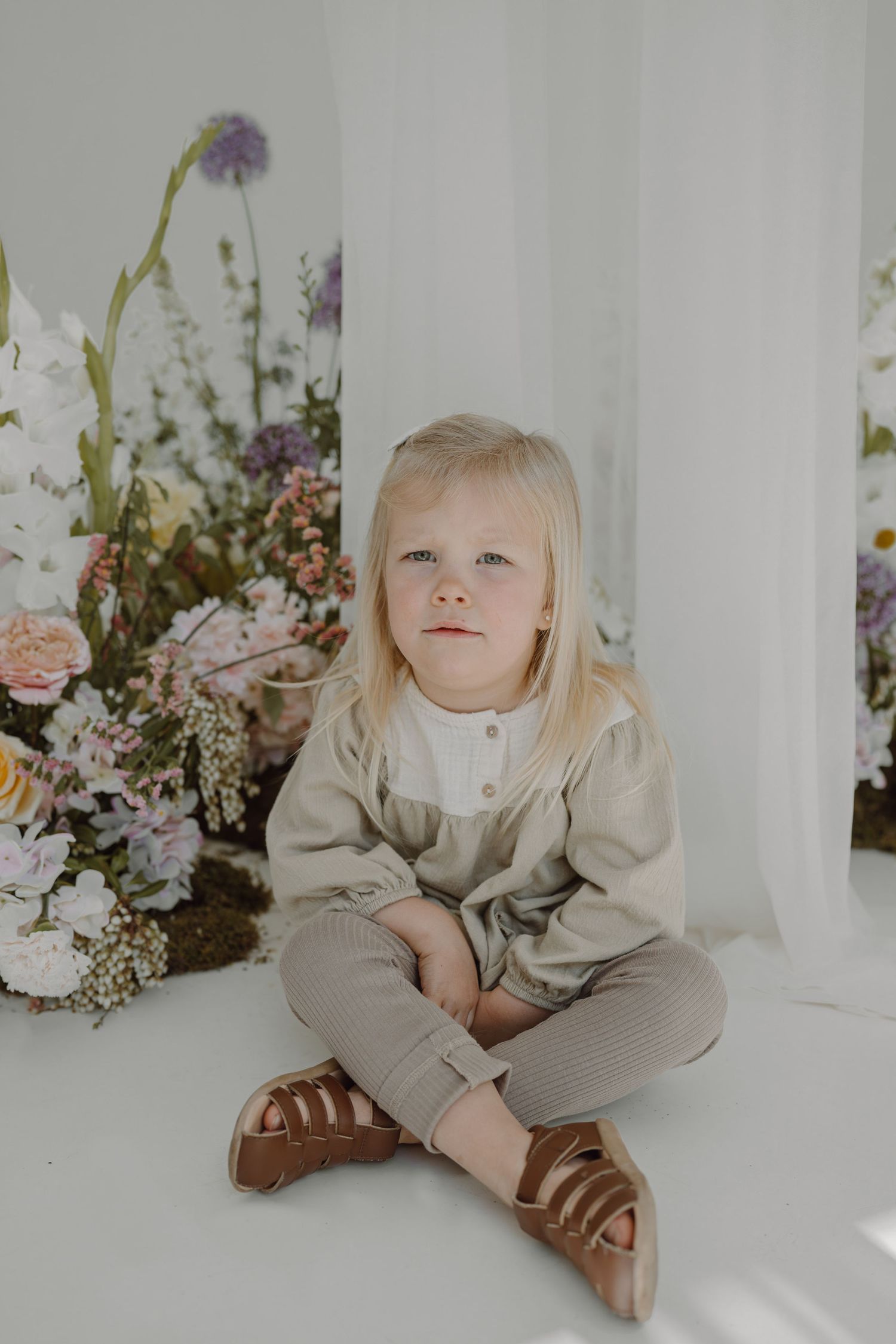 Light and airy studio setting with purple and white floral decorations.