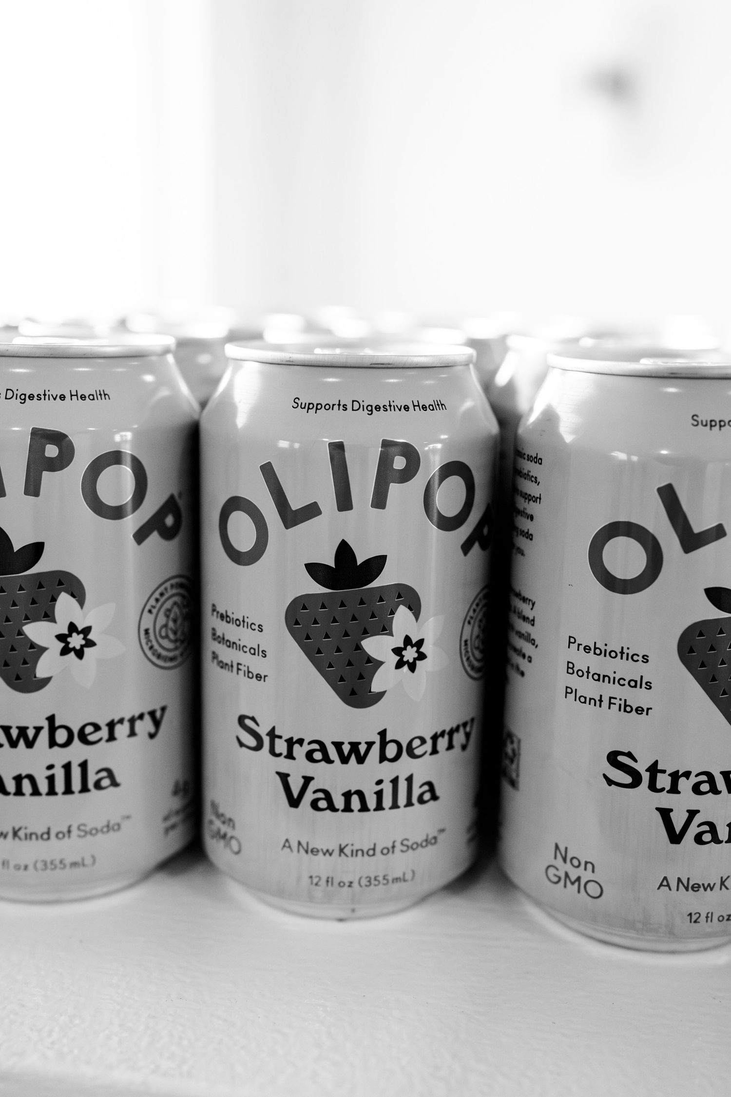 Line of Olipop soda cans showing different flavors in black and white.