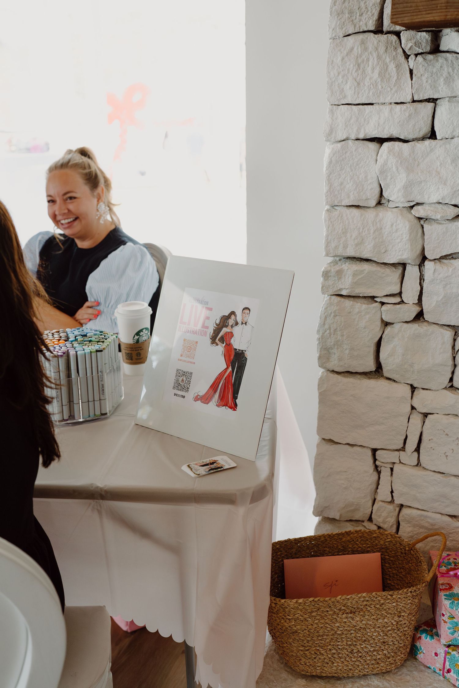 People sharing artwork and cards at a celebration with gift bags in the background.
