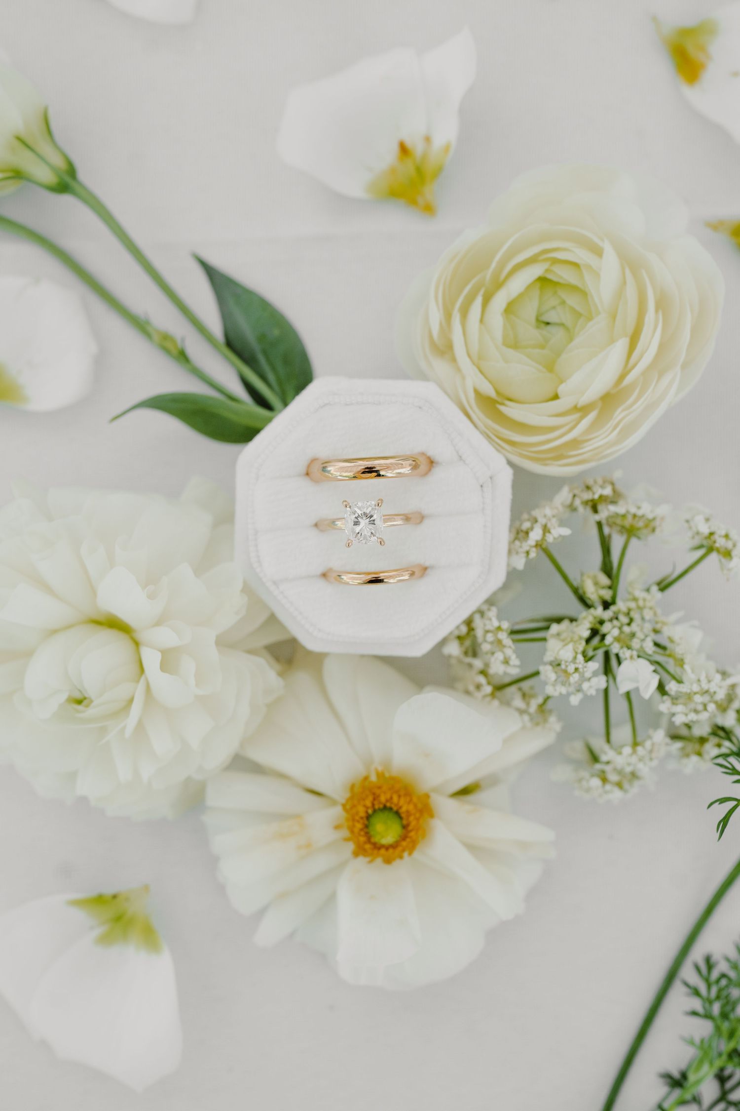 Wedding rings nestled among white roses and baby's breath on light background.