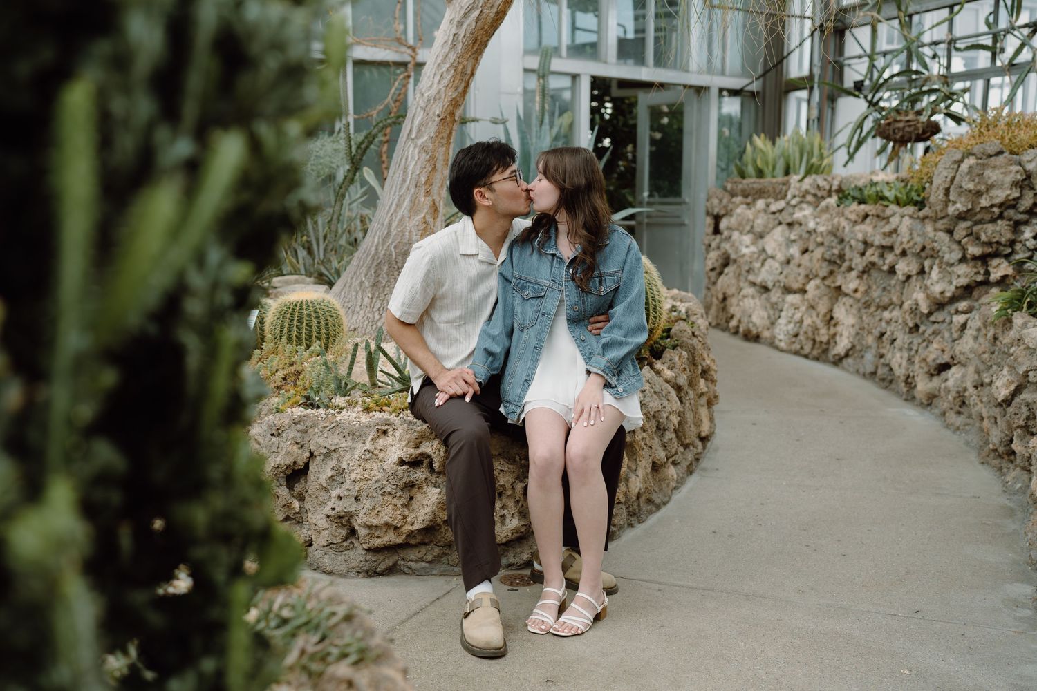 A couple sits together on stone steps in a botanical garden setting.