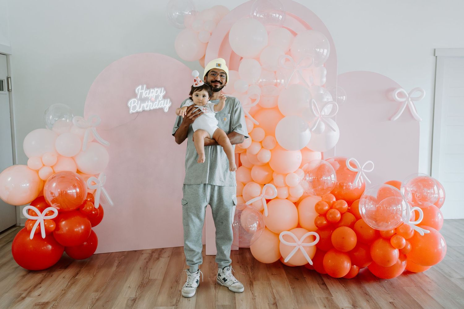 Modern birthday party backdrop with gradient balloon arrangement in coral and pink.