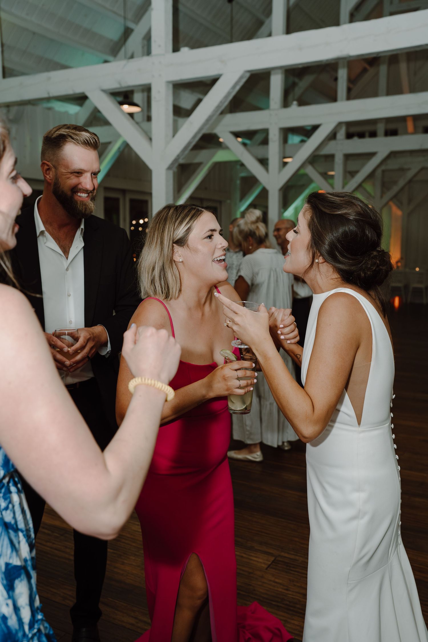Party guests laugh and dance together at a wedding reception in a rustic venue.