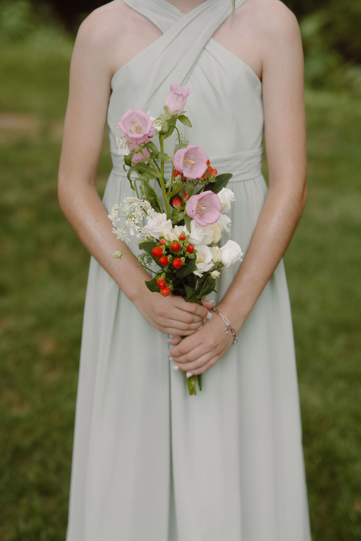 Close-up of bridesmaids holding pink and orange floral bouquets against mint green dresses.