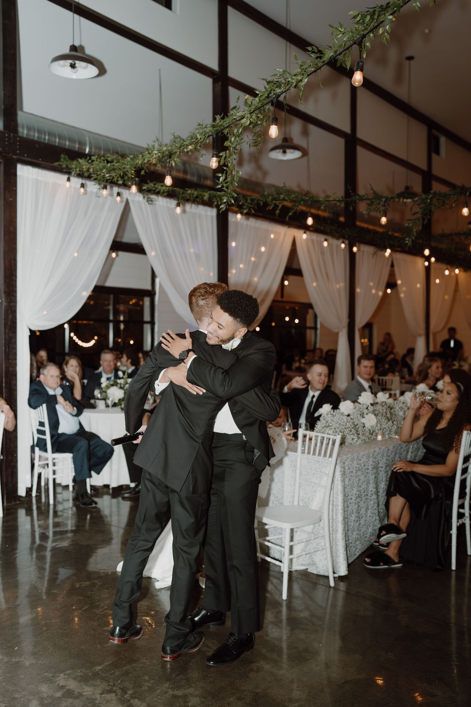 Guests performing choreographed dance moves at a wedding reception under string lights.