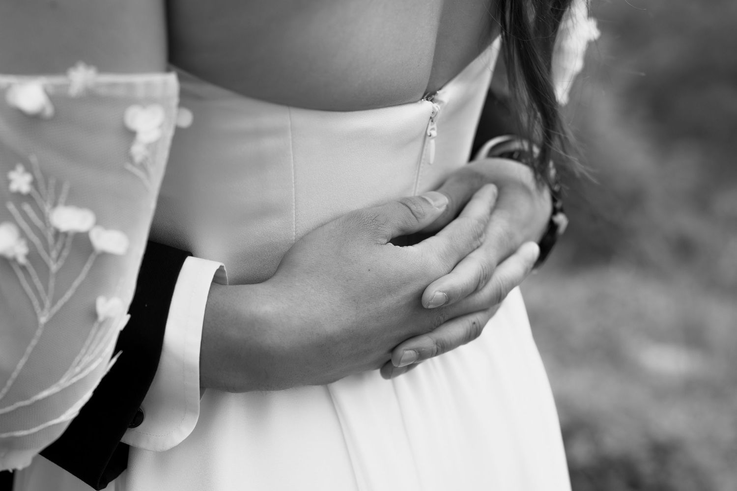 A tender wedding moment captured in black and white showing gentle embraces and intimate details.