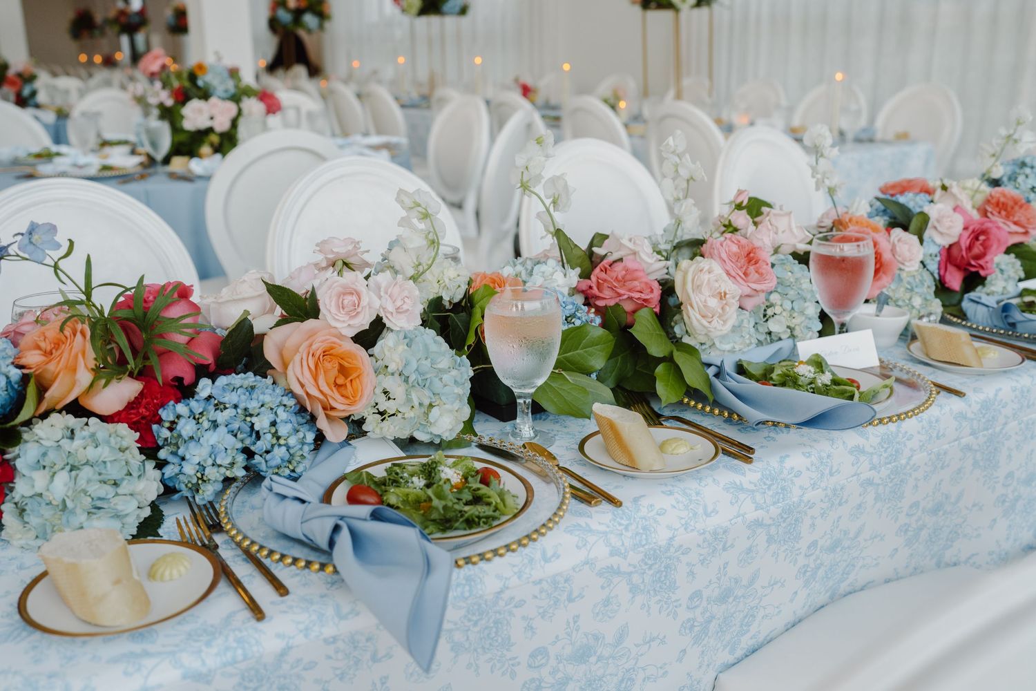 Elegant wedding reception table setting with pink floral arrangements and delicate place settings.