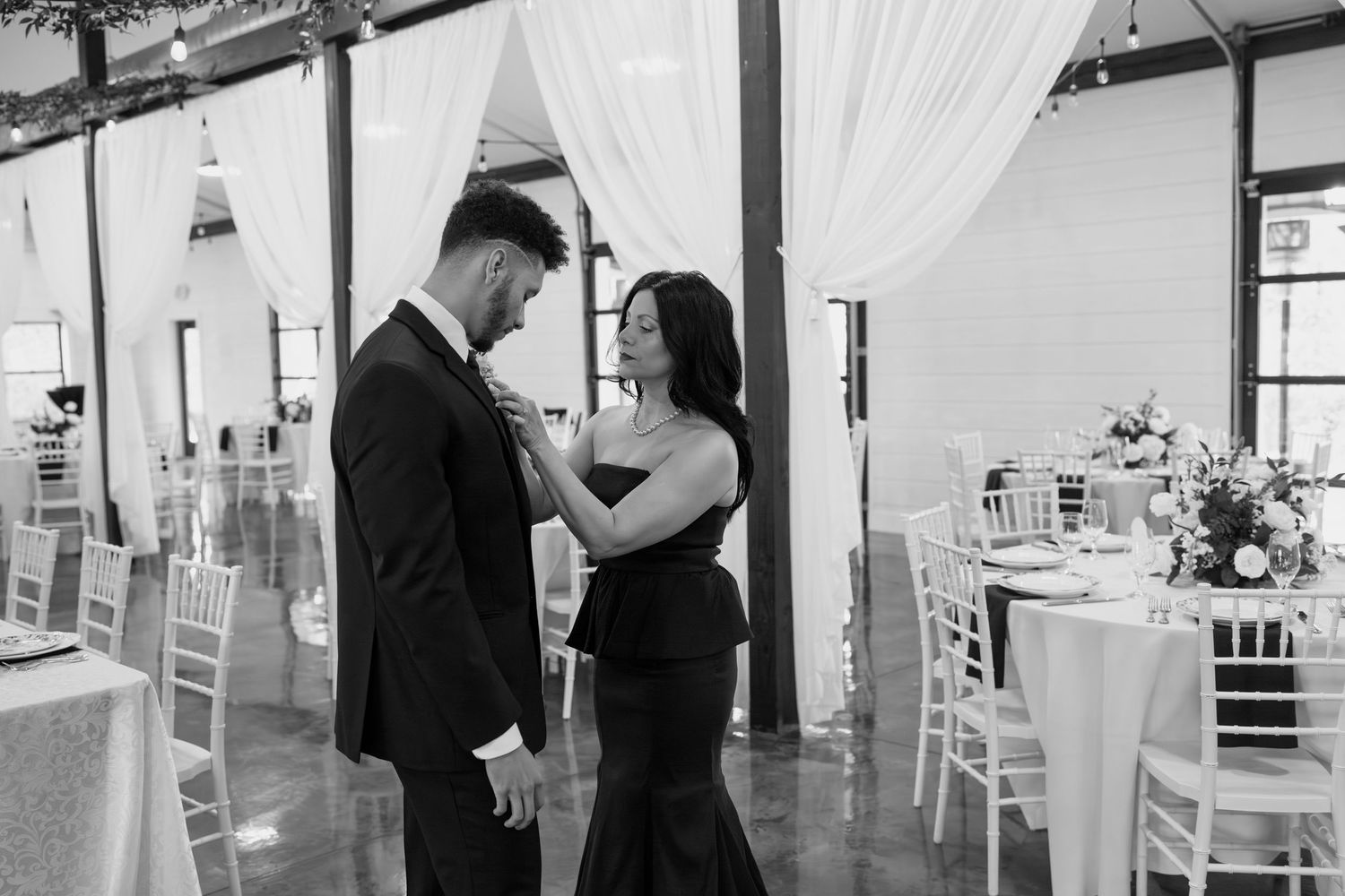 An elegant indoor venue decorated with white drapes and chairs set up for a special event.