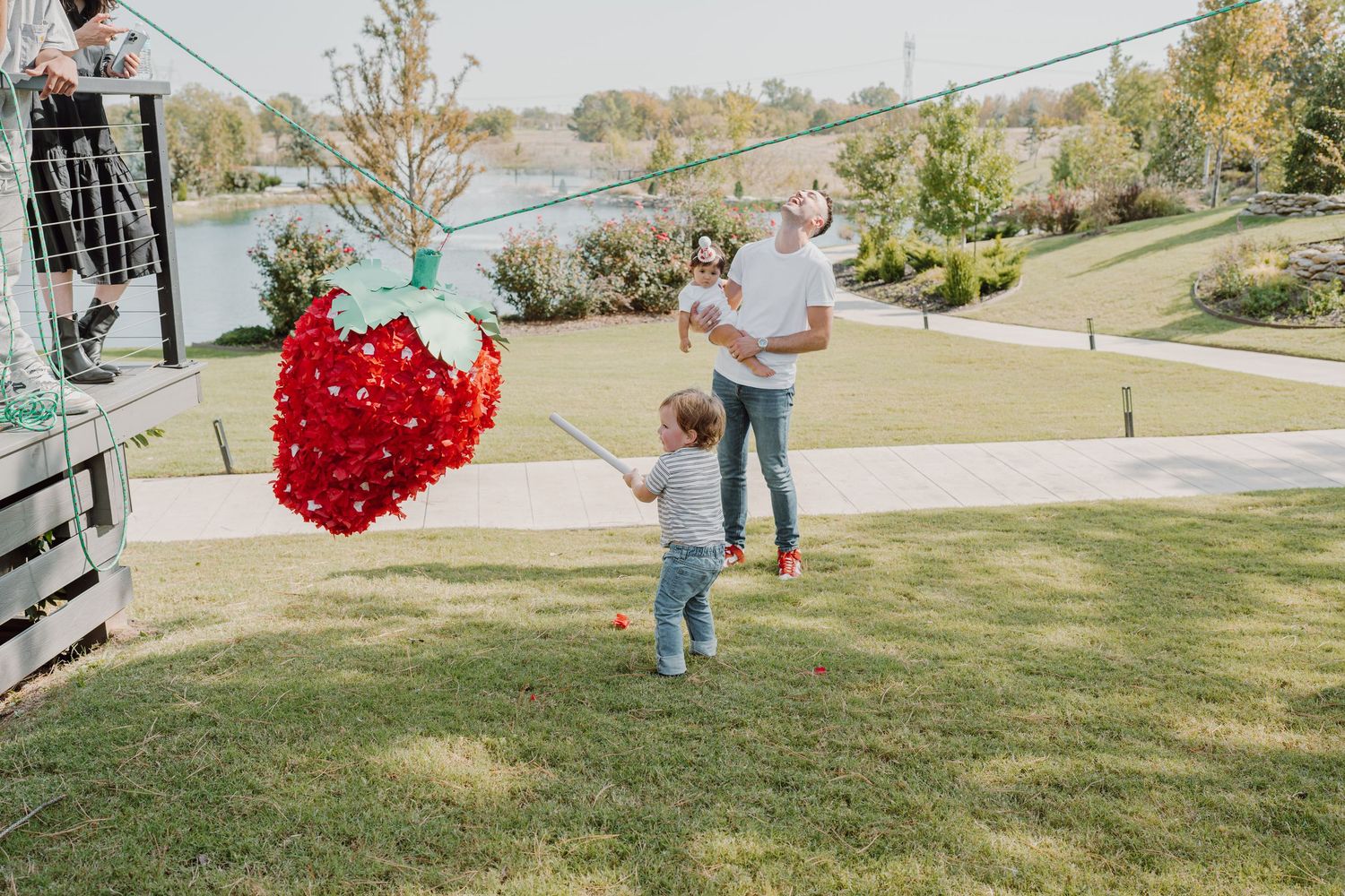 A festive red heart piñata swings back and forth on a grassy hill.