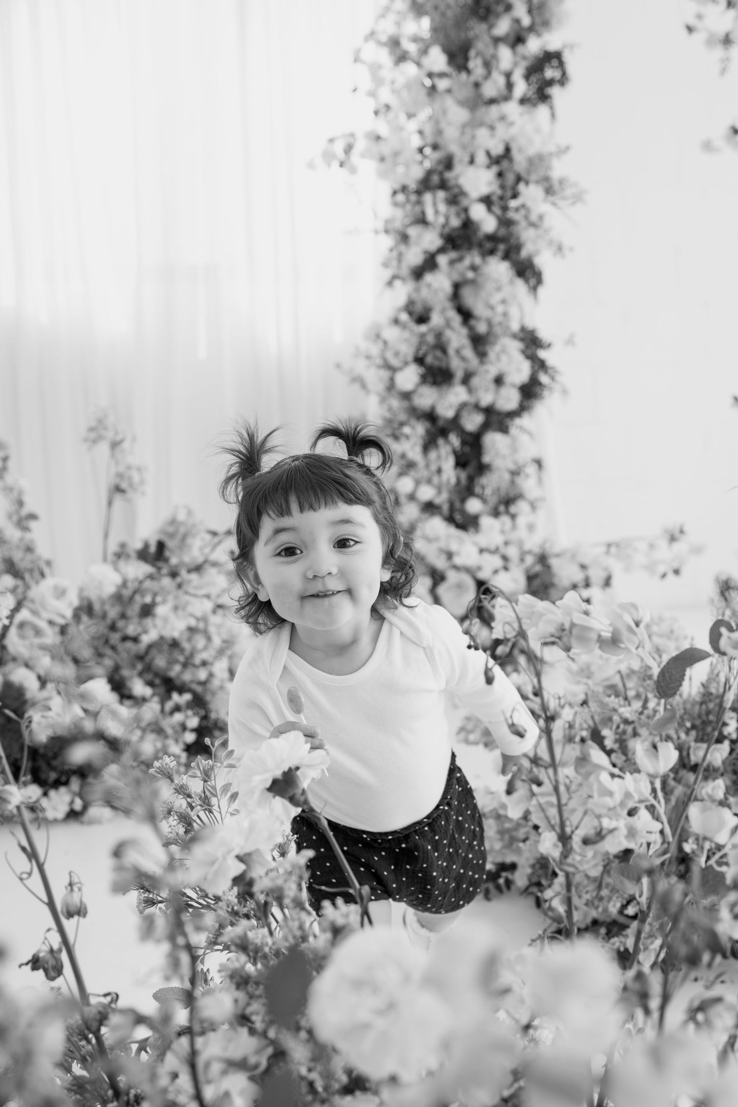 Child surrounded by delicate cherry blossoms in black and white photography.
