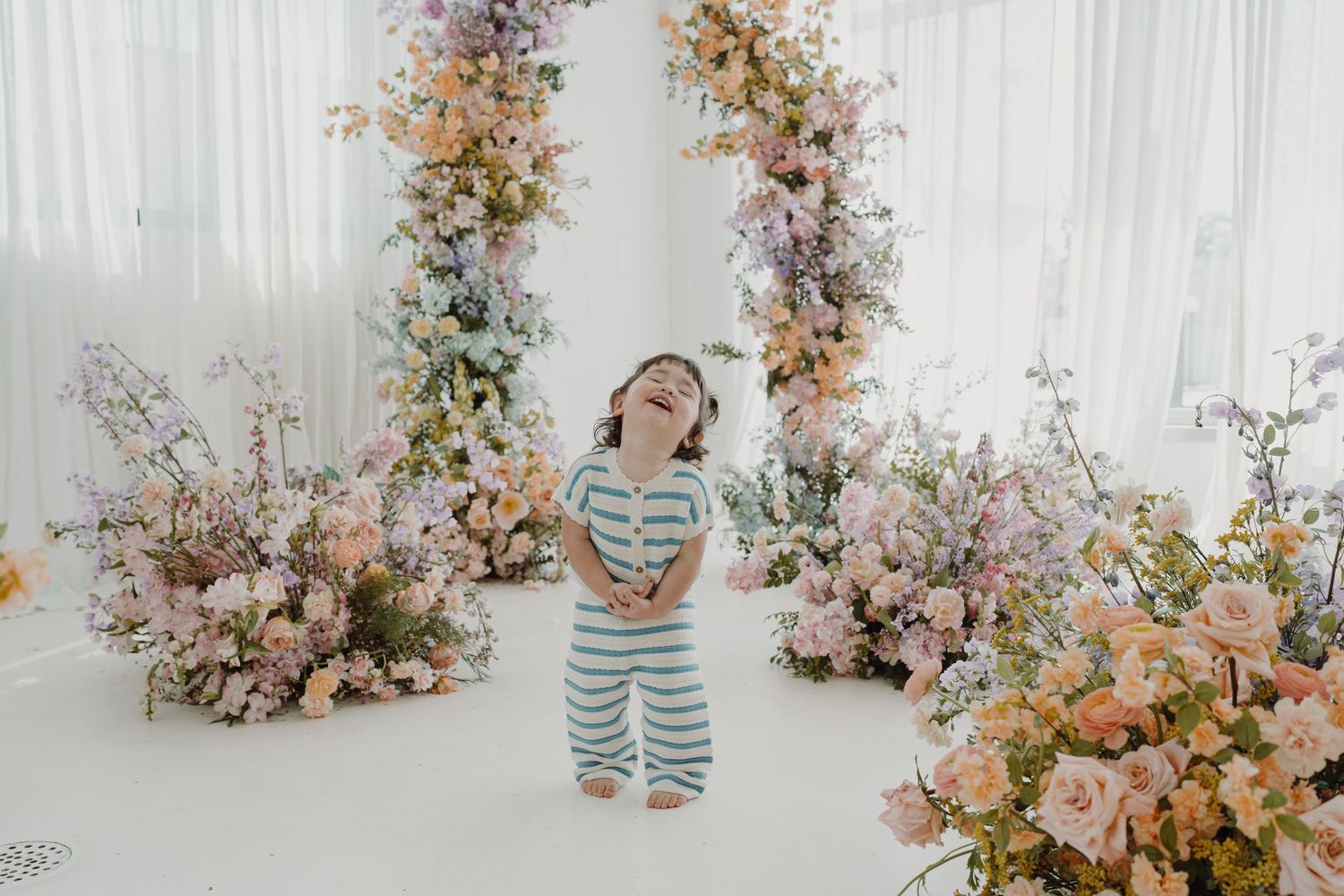 Light and airy studio space decorated with romantic floral installations in pink and peach.
