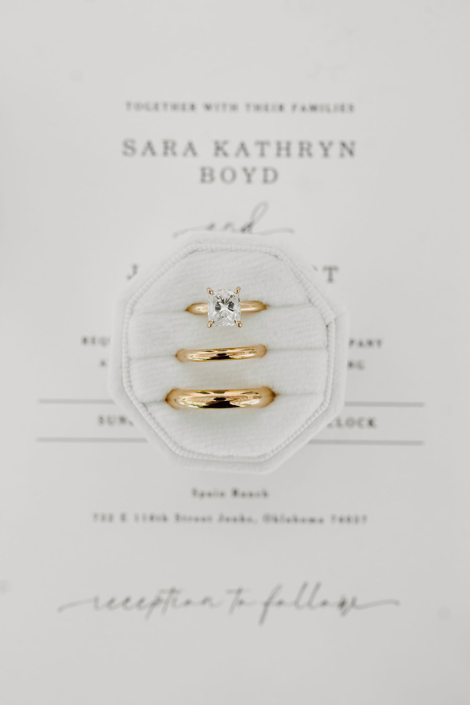 Wedding rings and invitation details photographed on elegant white stationery.