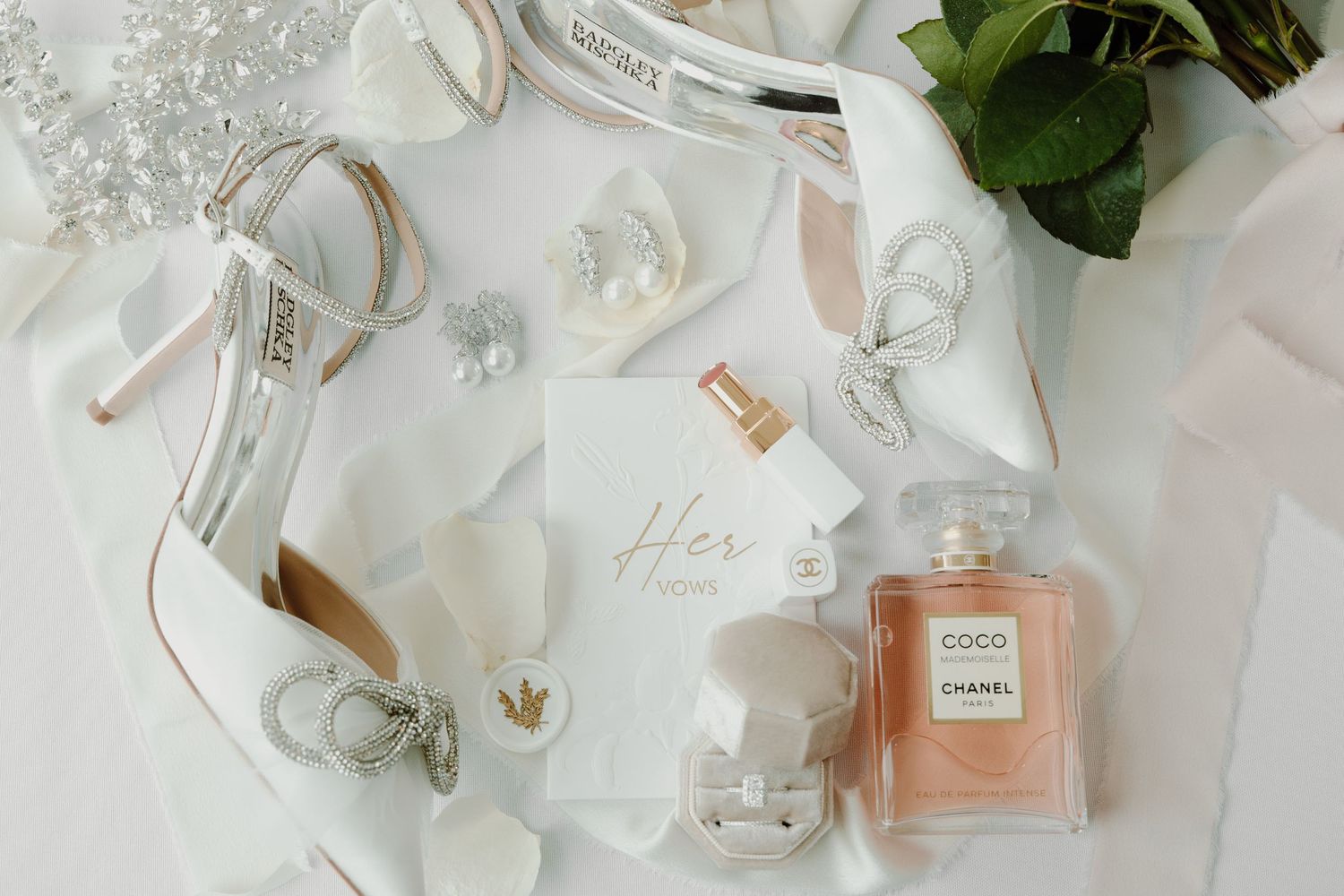 Wedding day details including perfume bottles, jewelry and floral elements on white background.