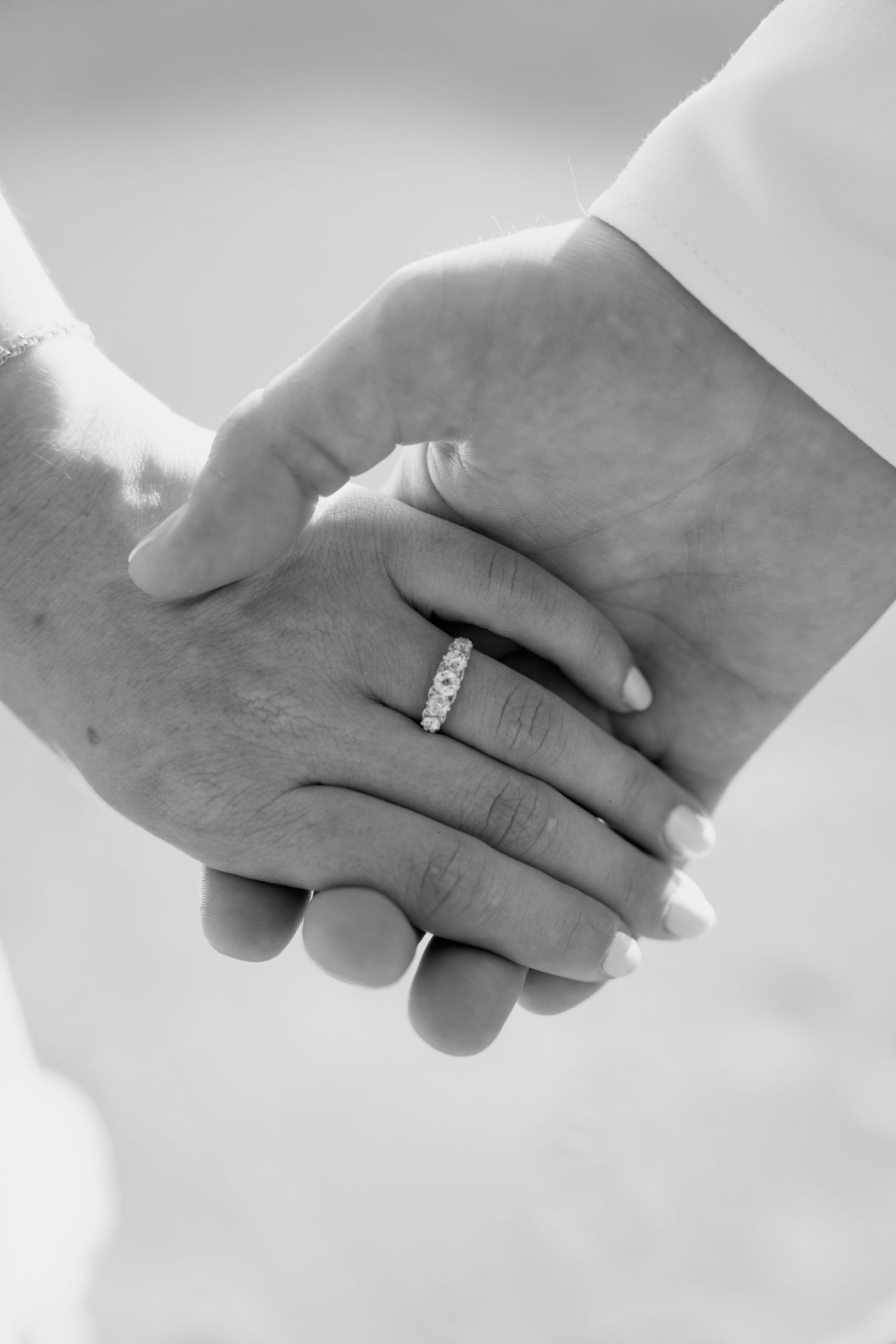 Black and white close-up shots of hands with engagement rings intertwined.