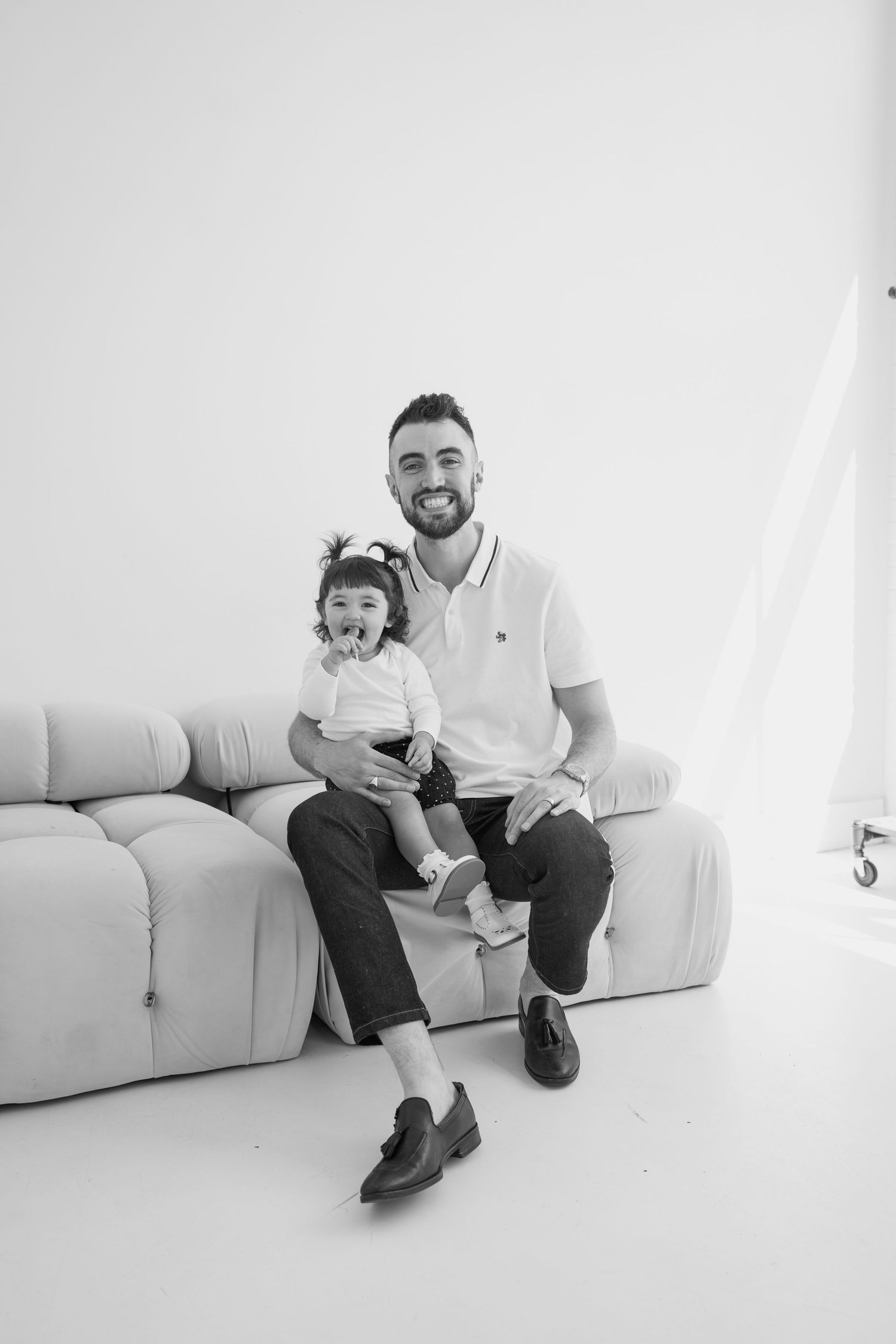 Black and white family portrait in a clean, modern studio setting.