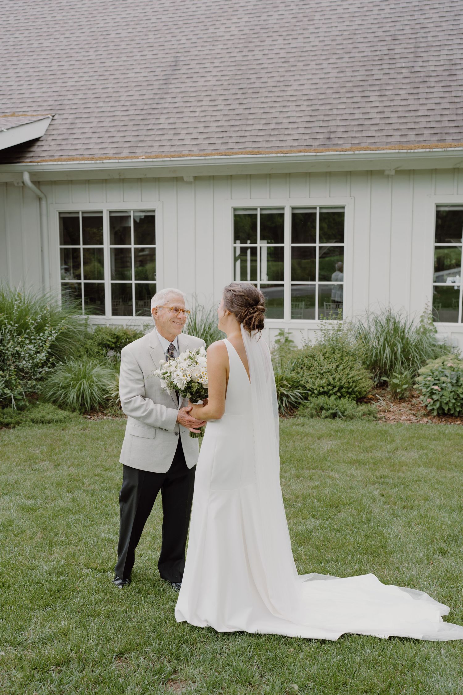 Emotional wedding first look moment between two people on a lawn.
